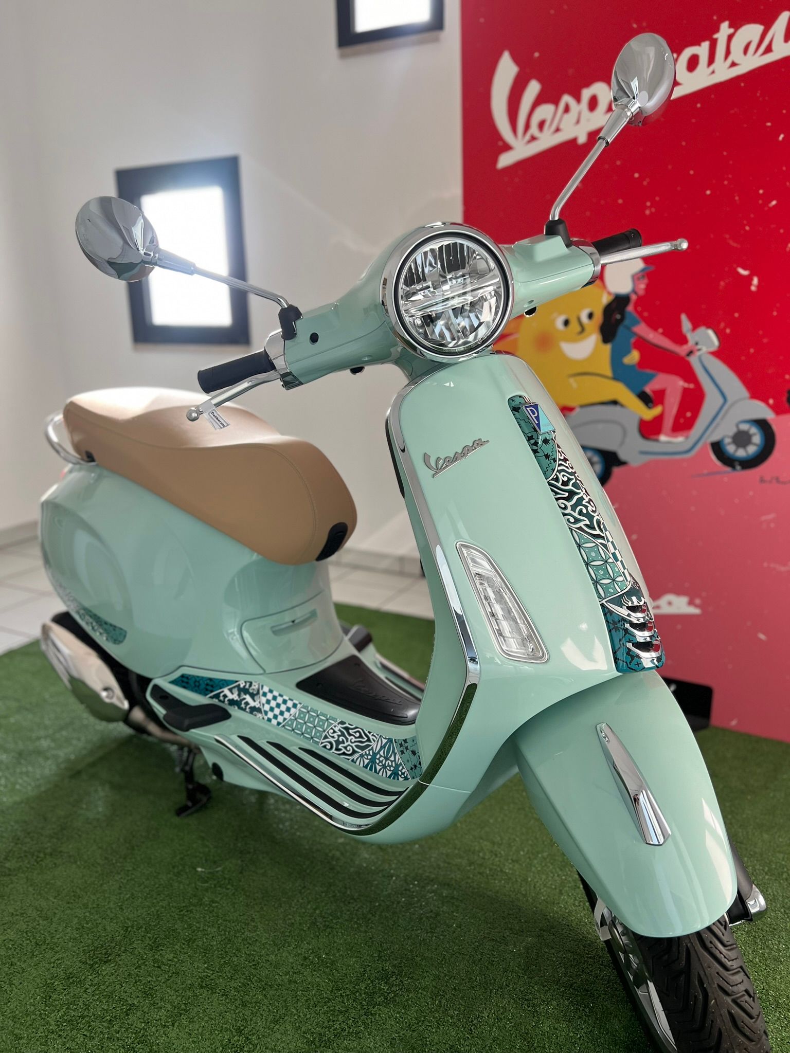 Una vespa verde è parcheggiata davanti a un cartello rosso.