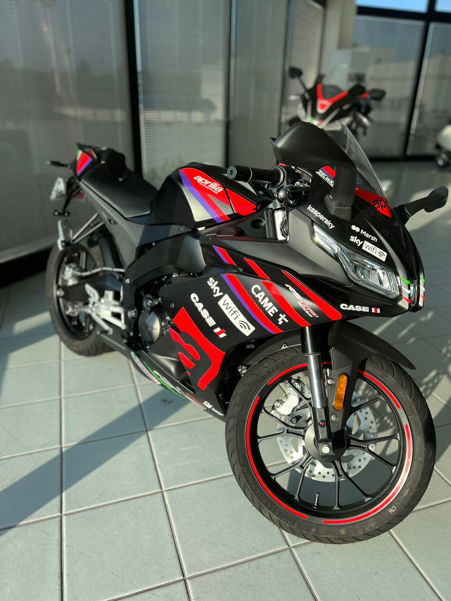 Una motocicletta rossa e nera è parcheggiata su un pavimento piastrellato in uno showroom.