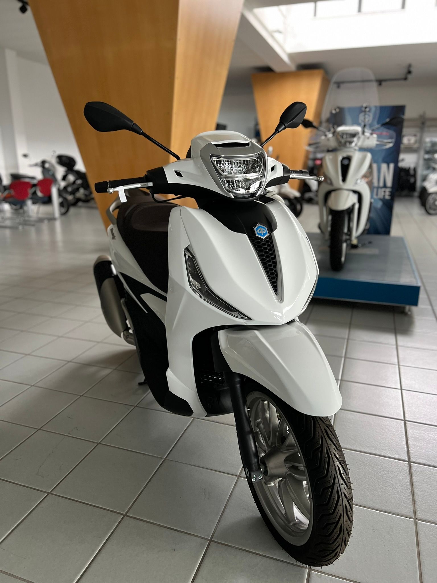 Uno scooter bianco è parcheggiato in uno showroom.
