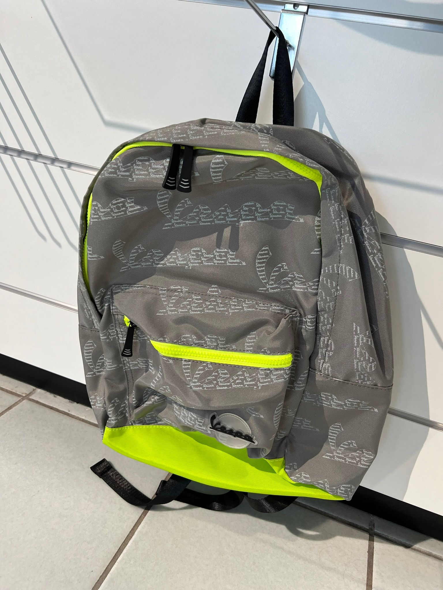 Uno zaino grigio e giallo è appeso a una parete.