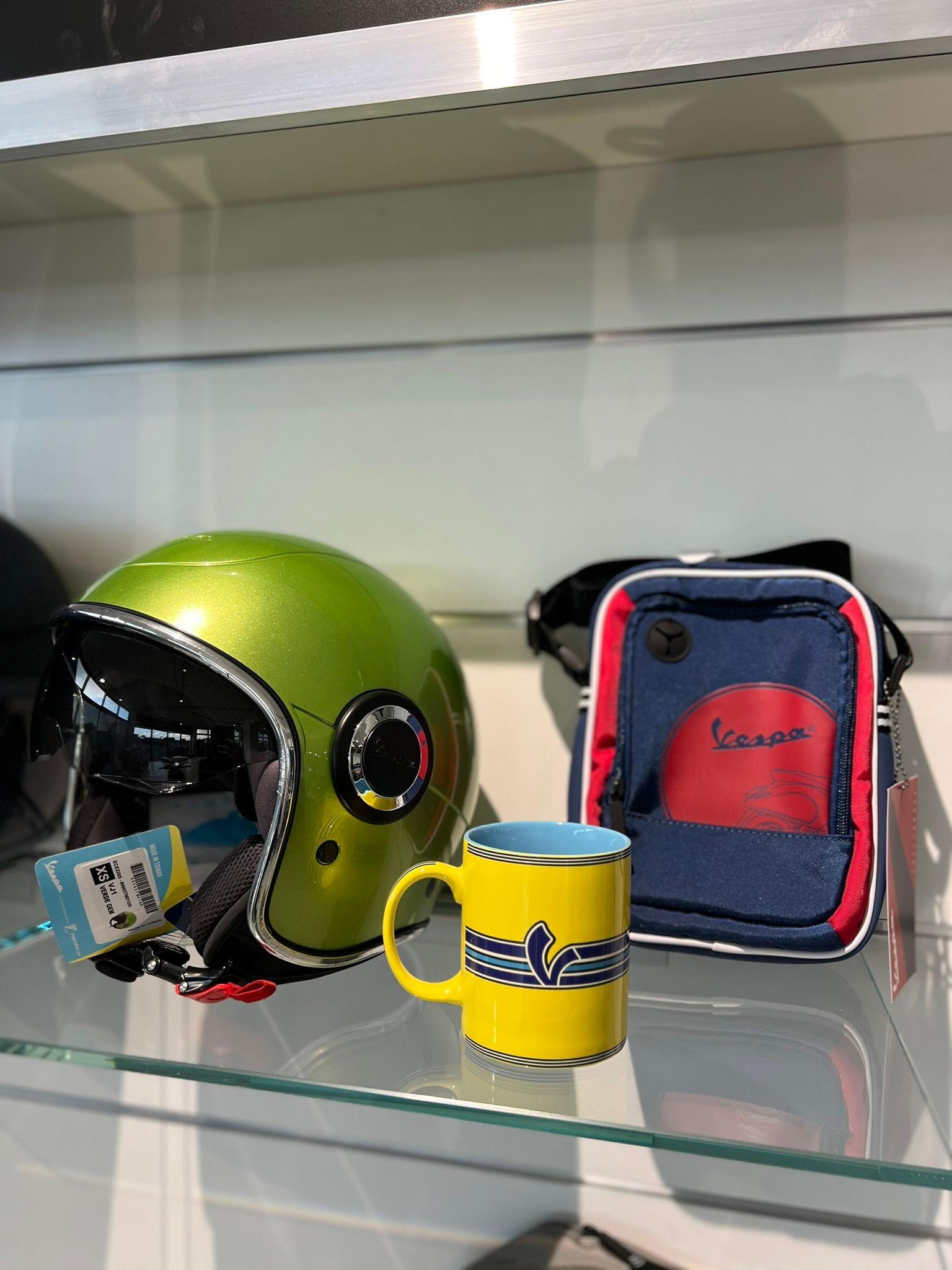 Un casco verde e una tazza gialla sono su uno scaffale di vetro.