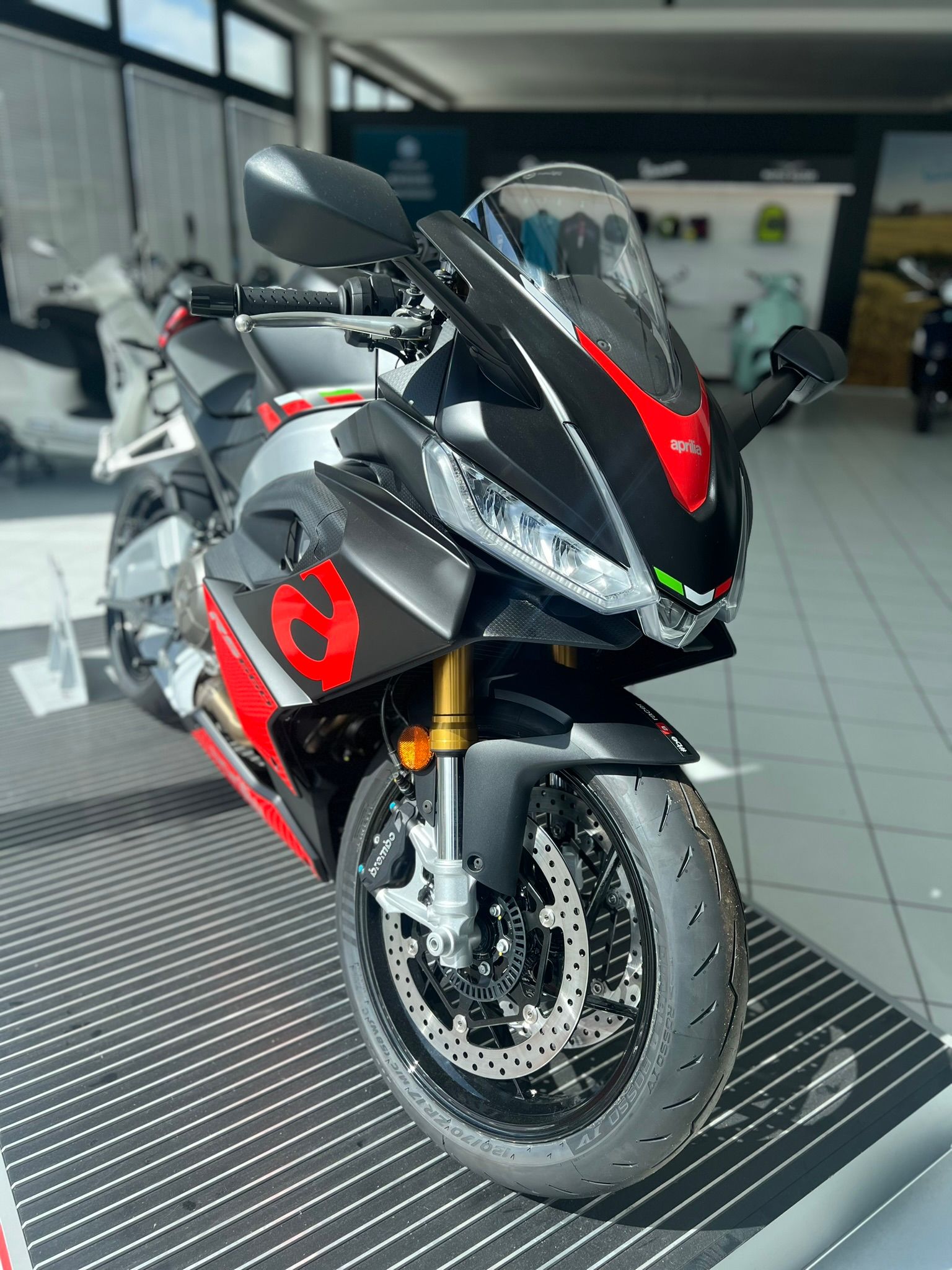 Una moto nera e rossa è parcheggiata in uno showroom.