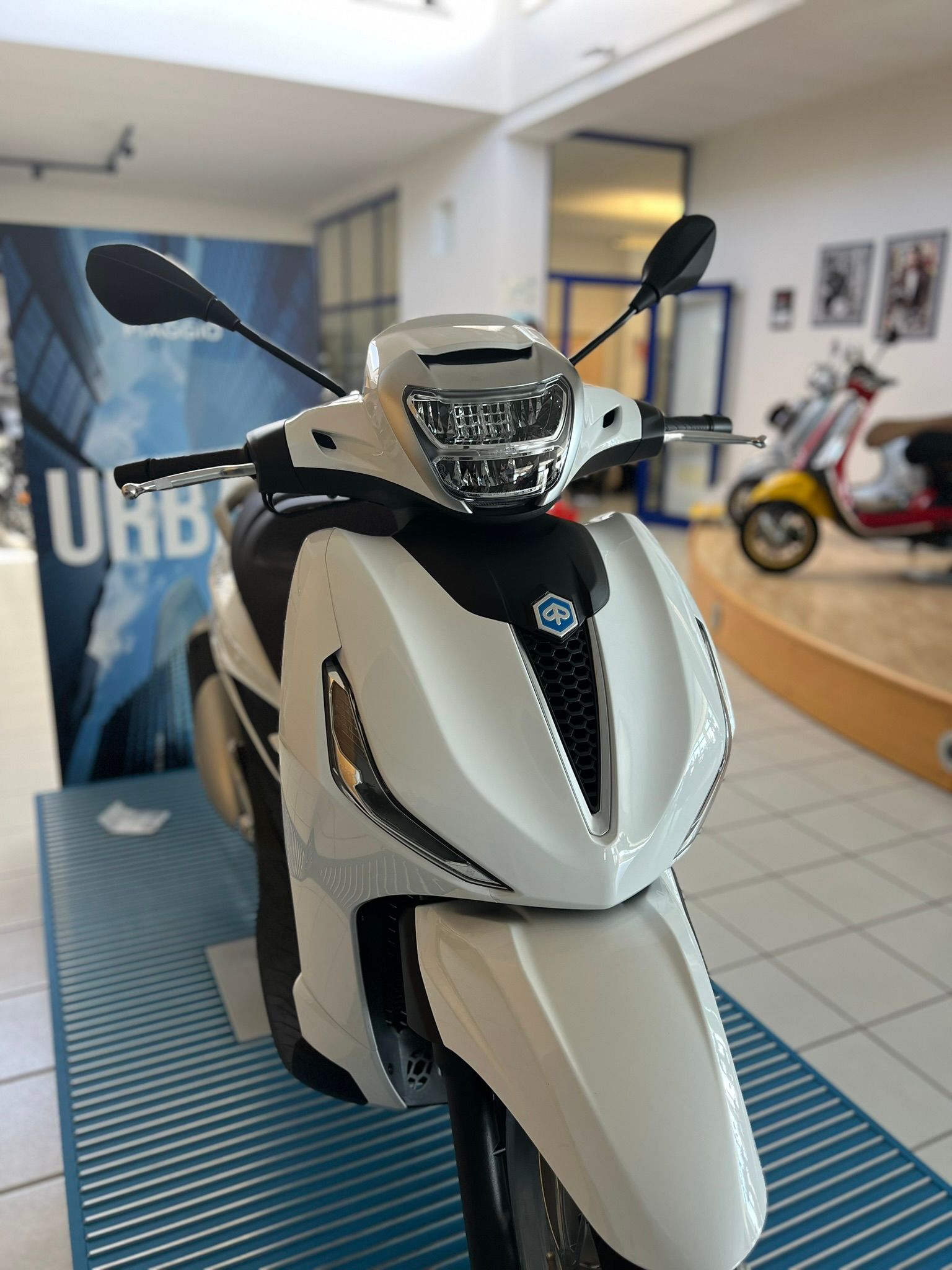 Uno scooter bianco è parcheggiato davanti a un cartello