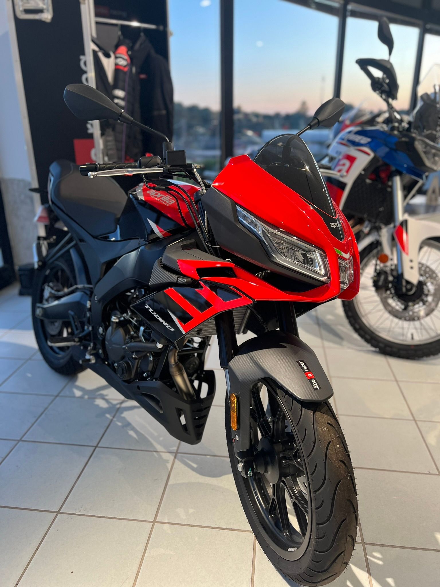 Una moto rossa e nera è parcheggiata in uno showroom.