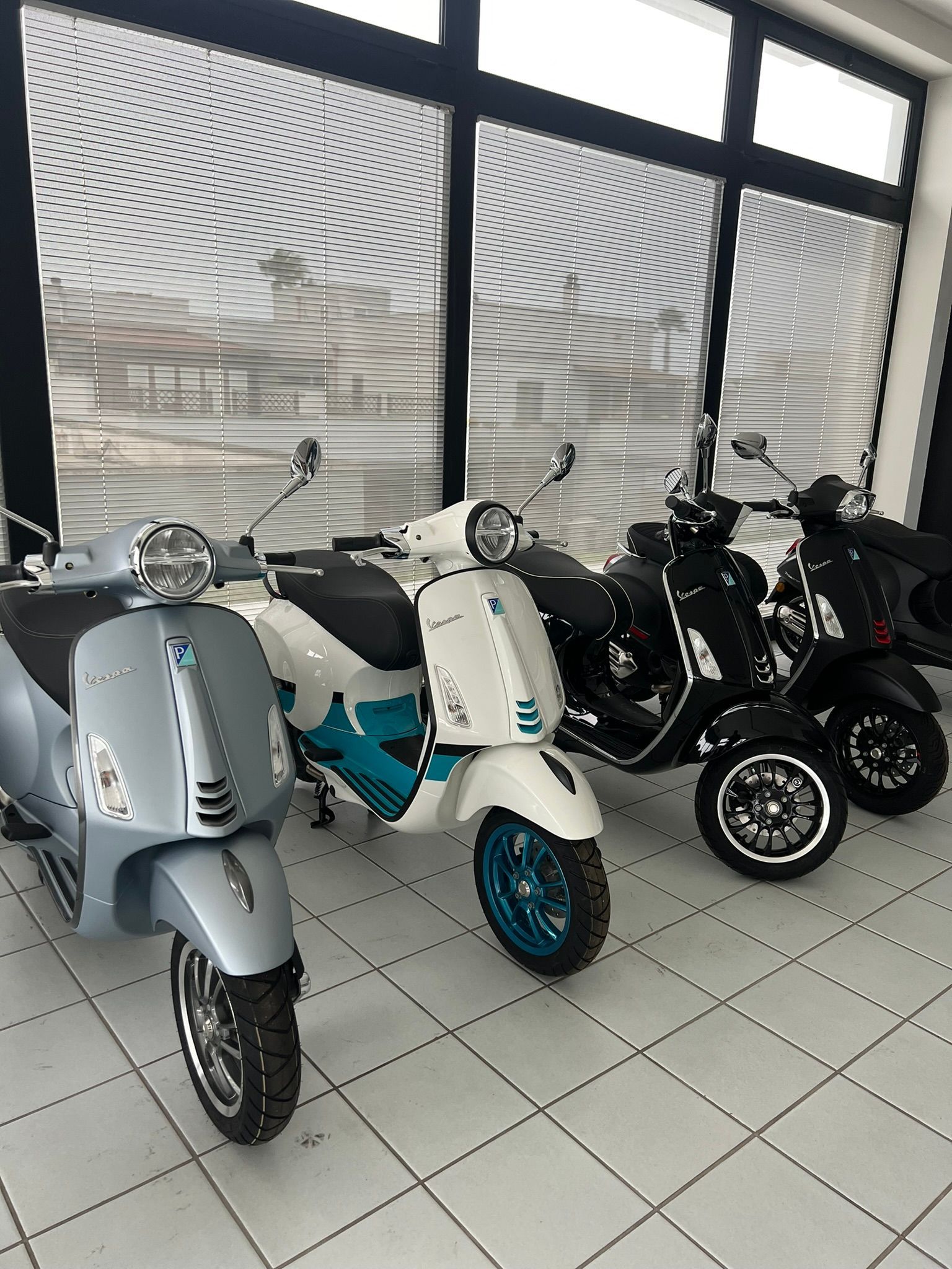 Una fila di scooter è parcheggiata in una stanza davanti a una finestra.