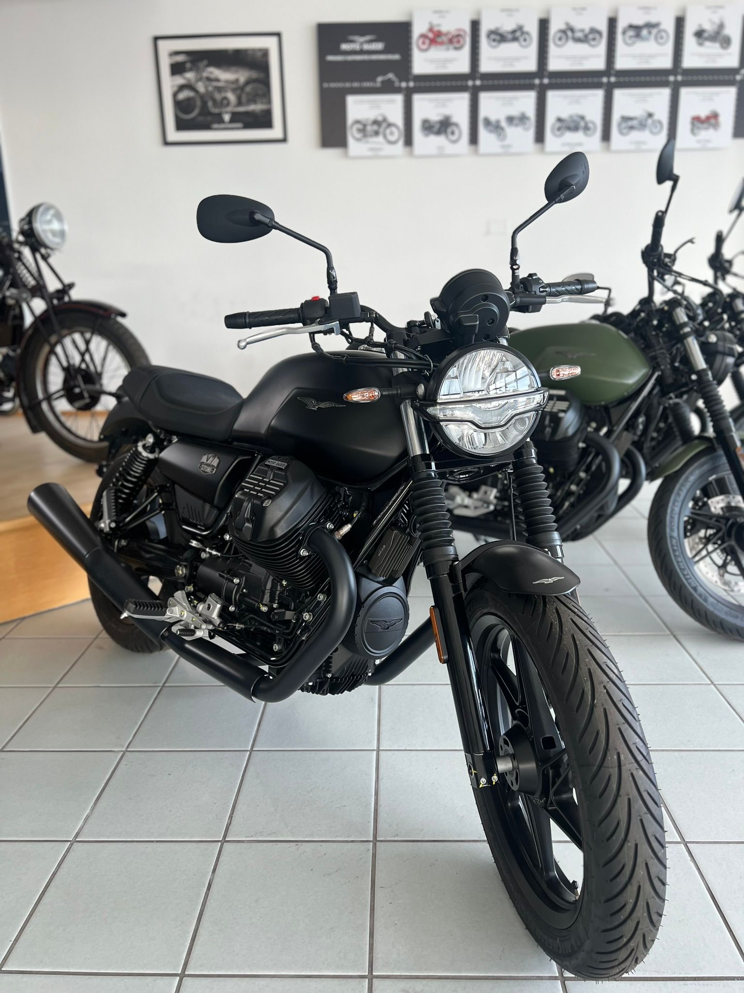 Una moto nera è parcheggiata in uno showroom accanto a una moto verde.