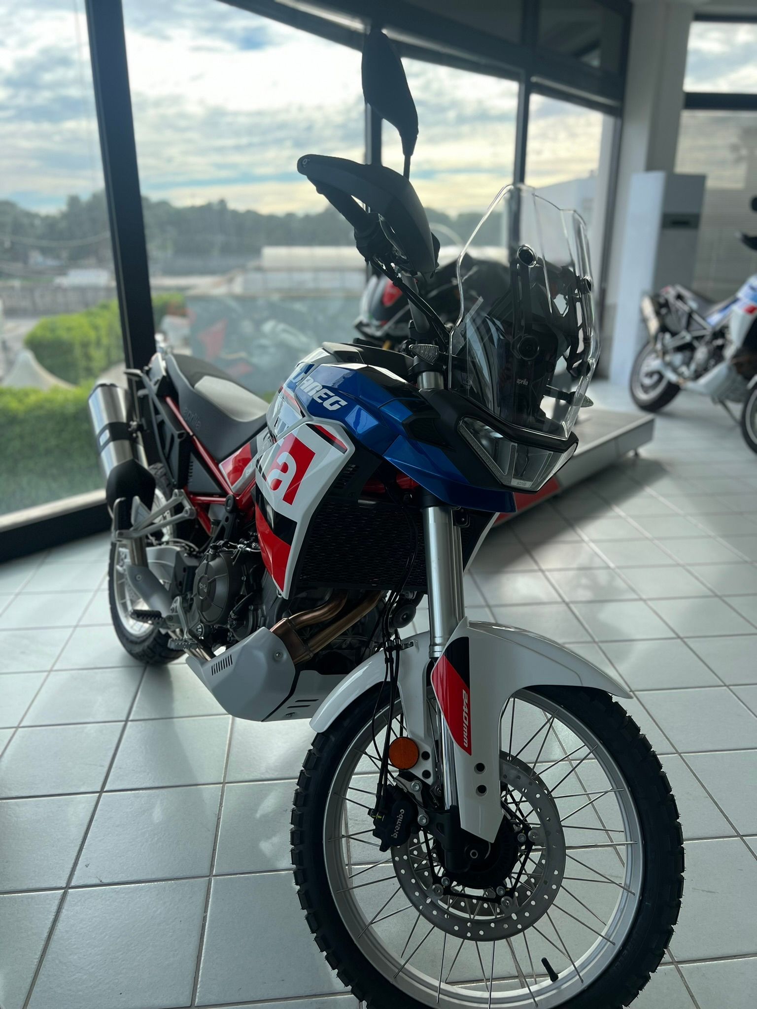 Una moto rossa, bianca e blu è parcheggiata in uno showroom.