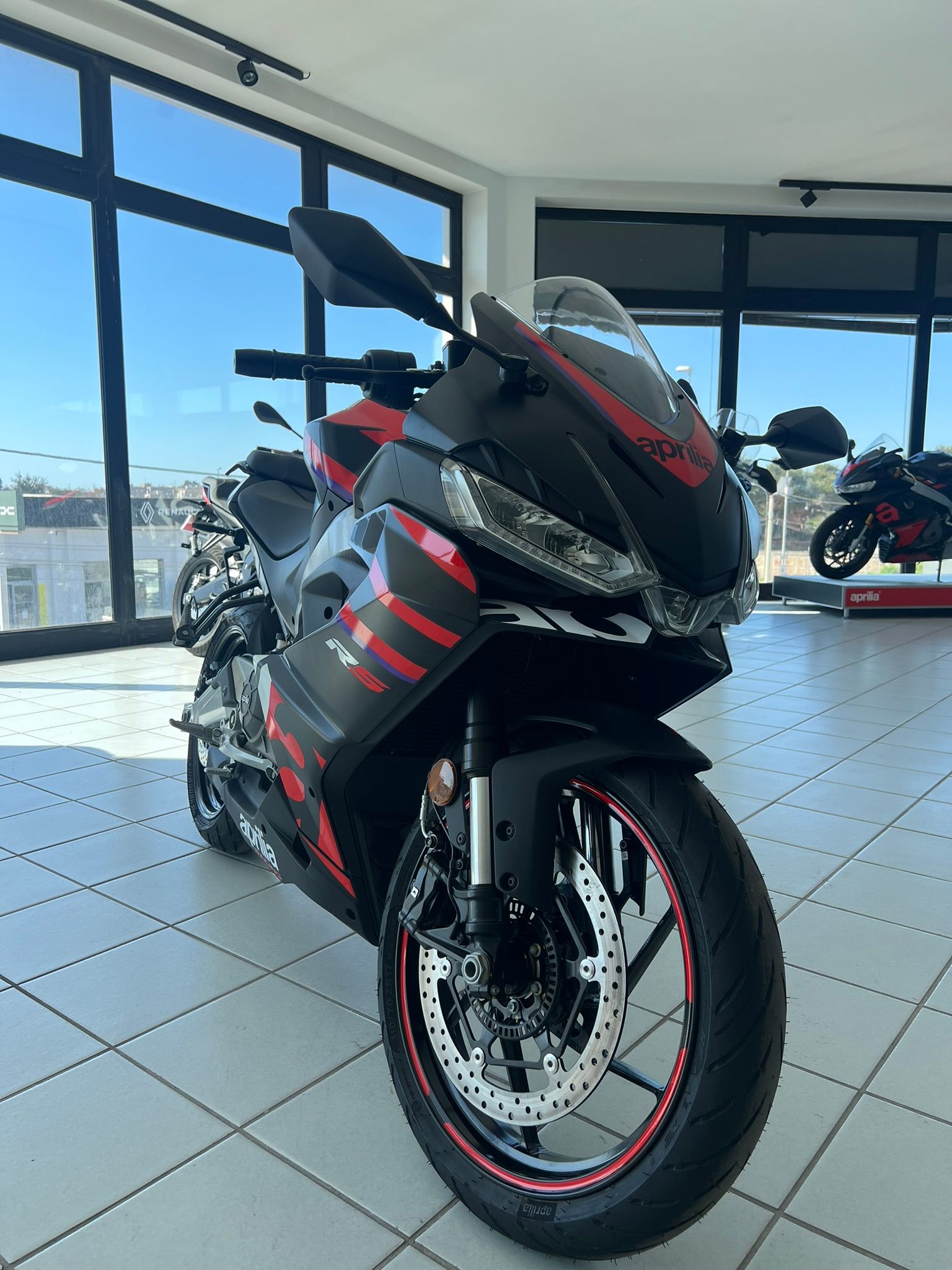 Una moto nera e rossa è parcheggiata in uno showroom.