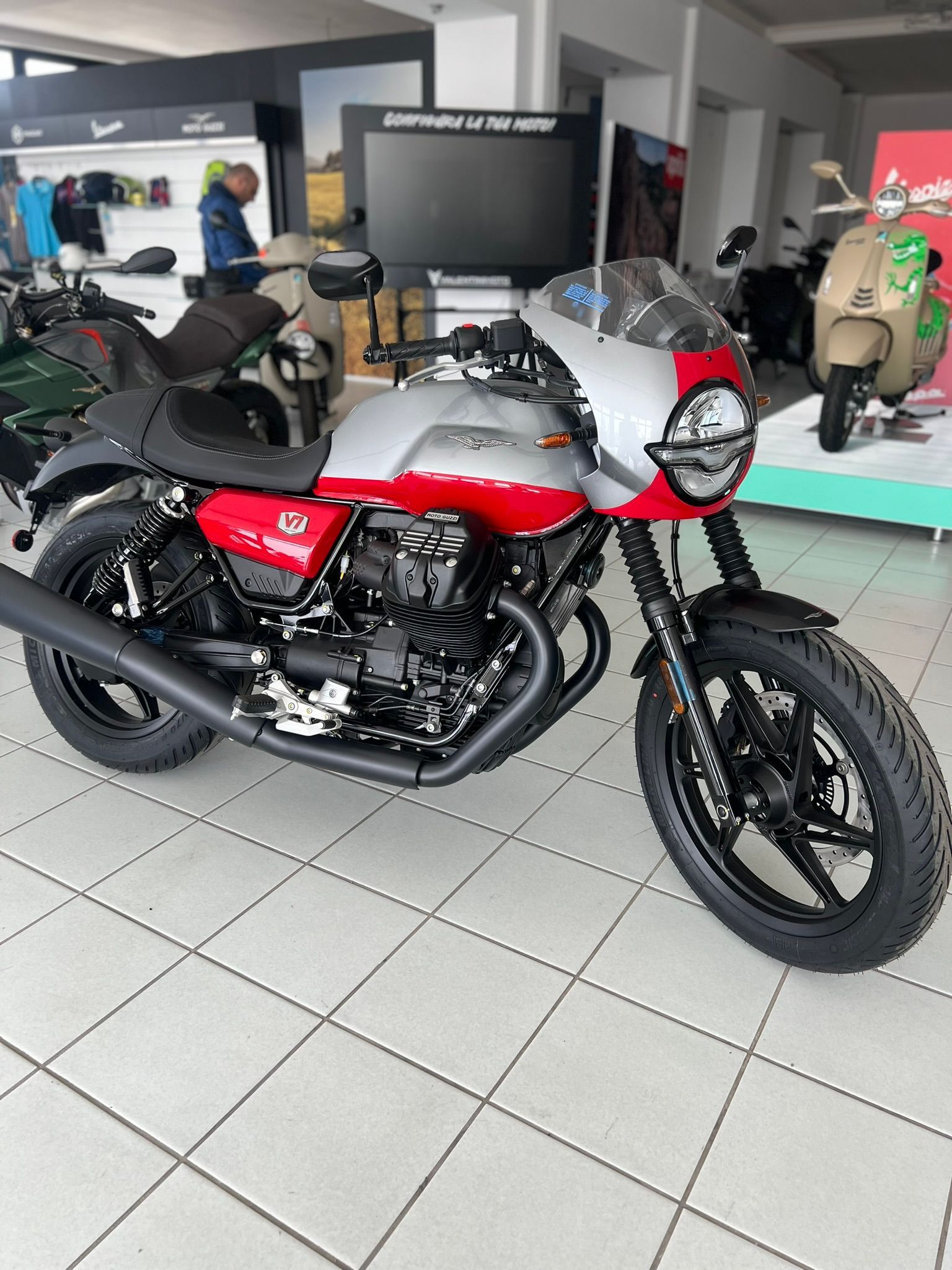 Una moto rossa e bianca è parcheggiata in uno showroom.