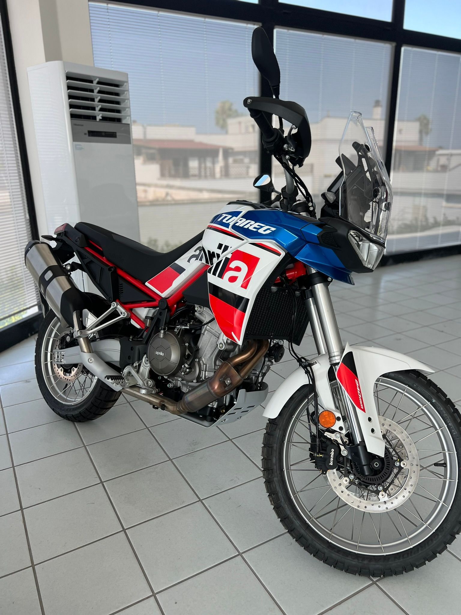 Una moto rossa, bianca e blu è parcheggiata in uno showroom.