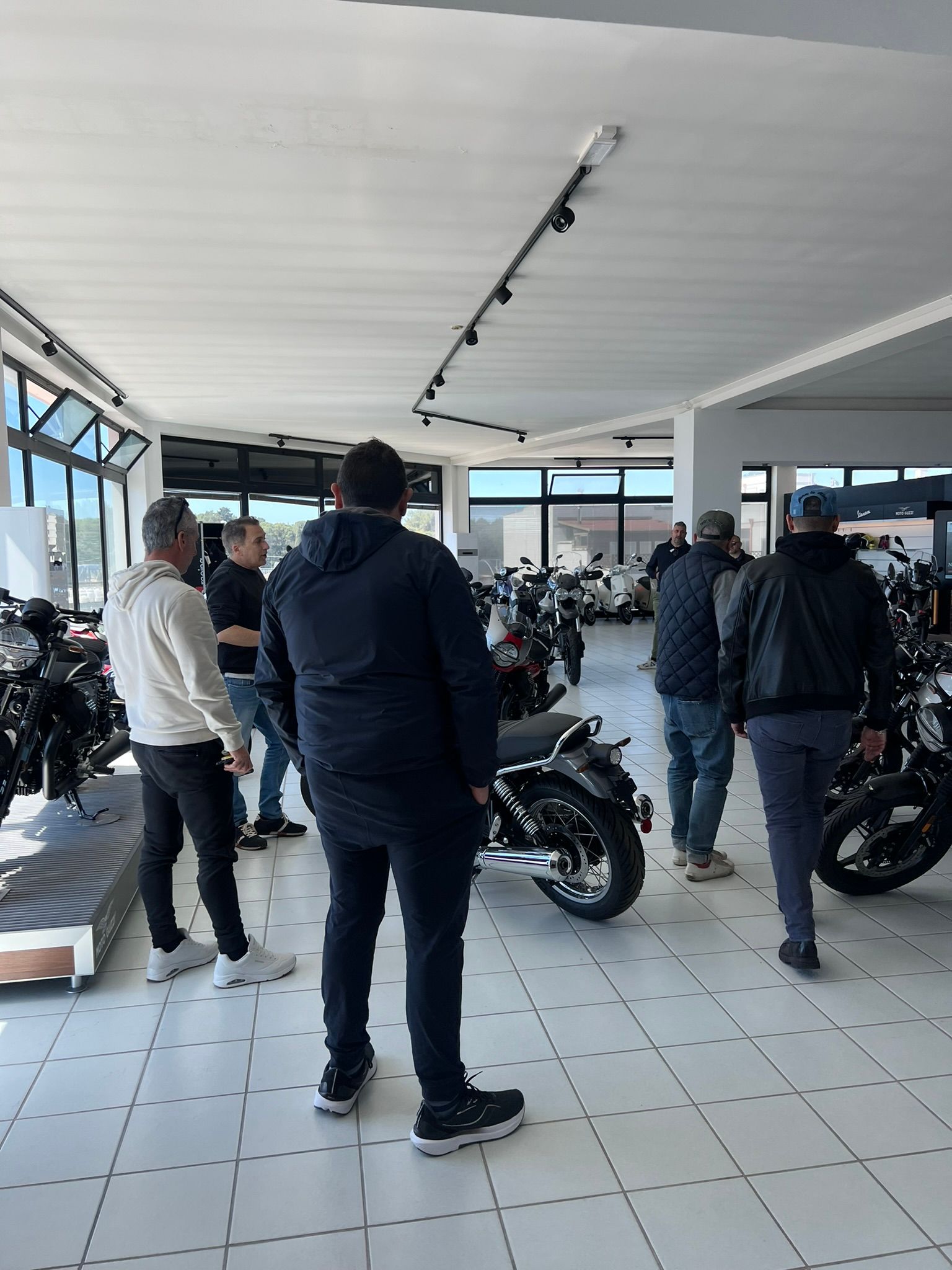 Un gruppo di uomini è in piedi in una stanza e guarda le moto.