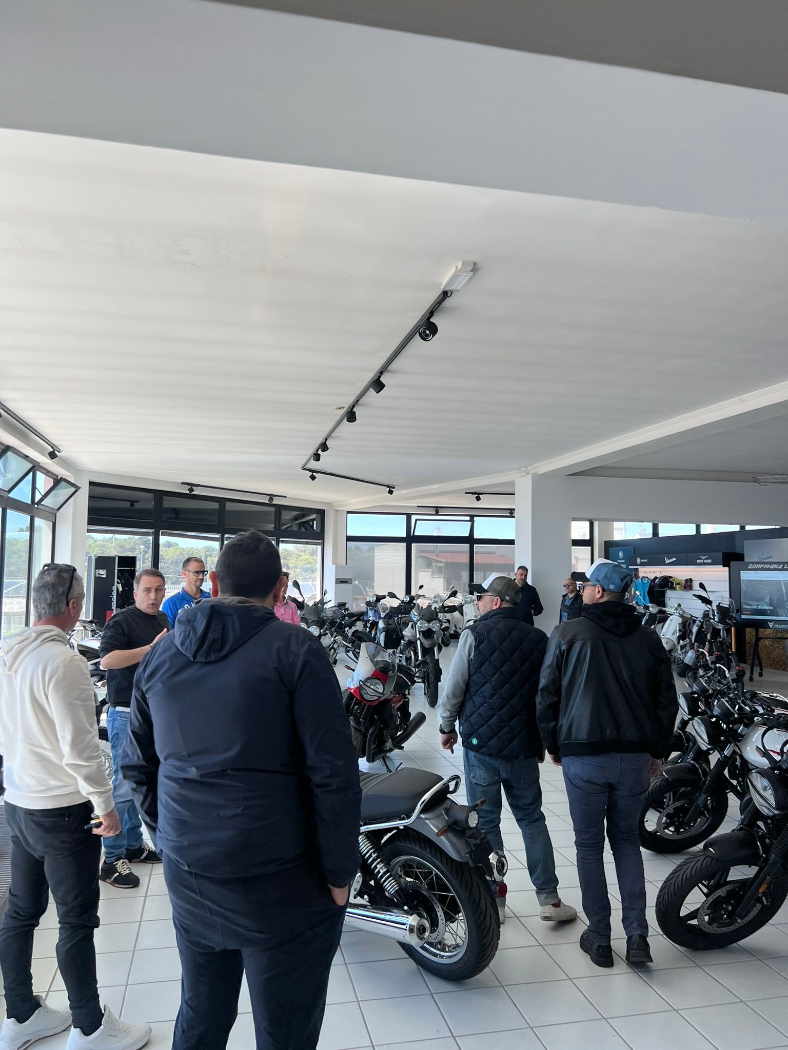 Un gruppo di uomini è in piedi in una stanza e guarda le moto.