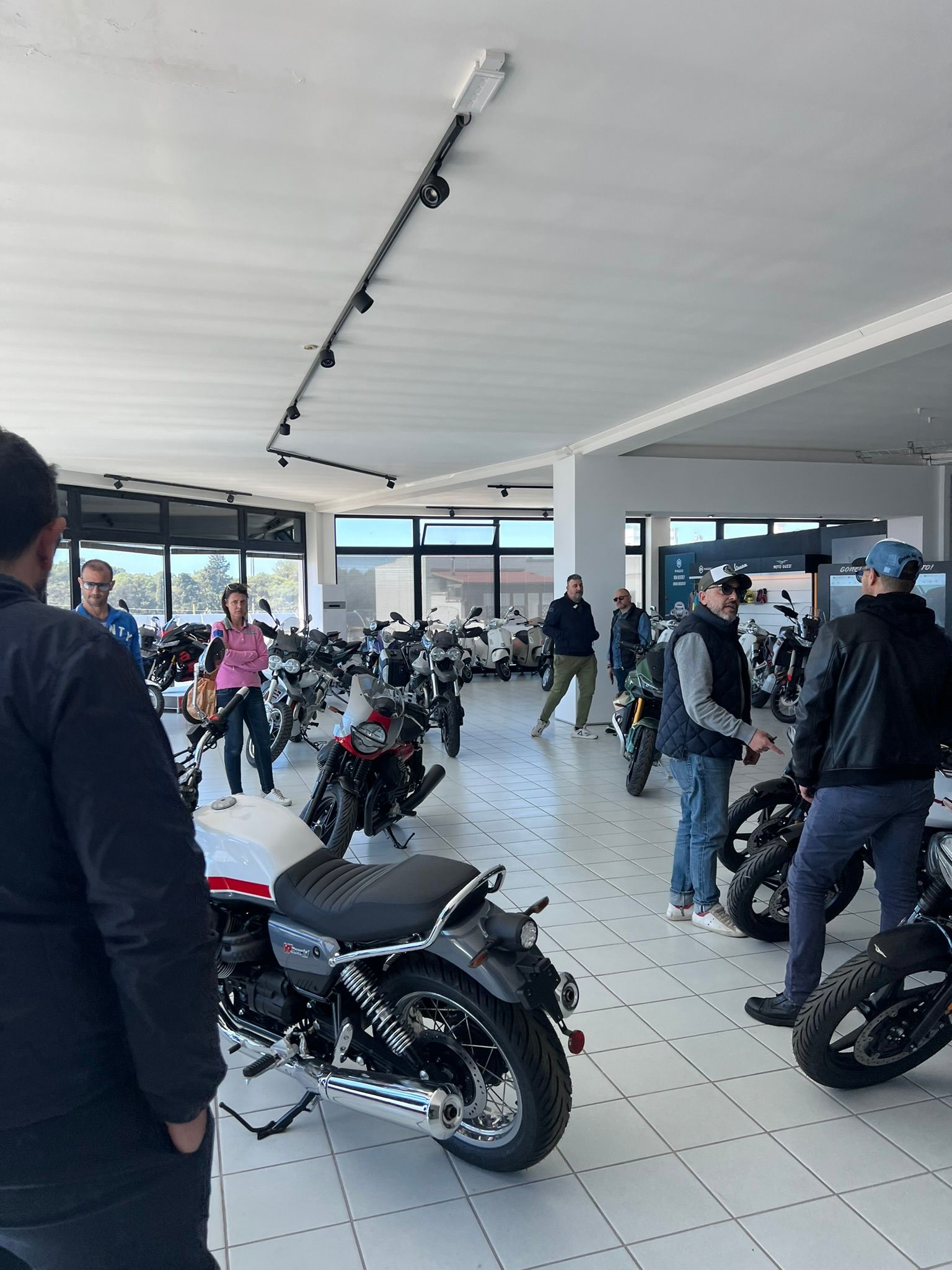 Un gruppo di persone è in piedi attorno alle moto in uno showroom.