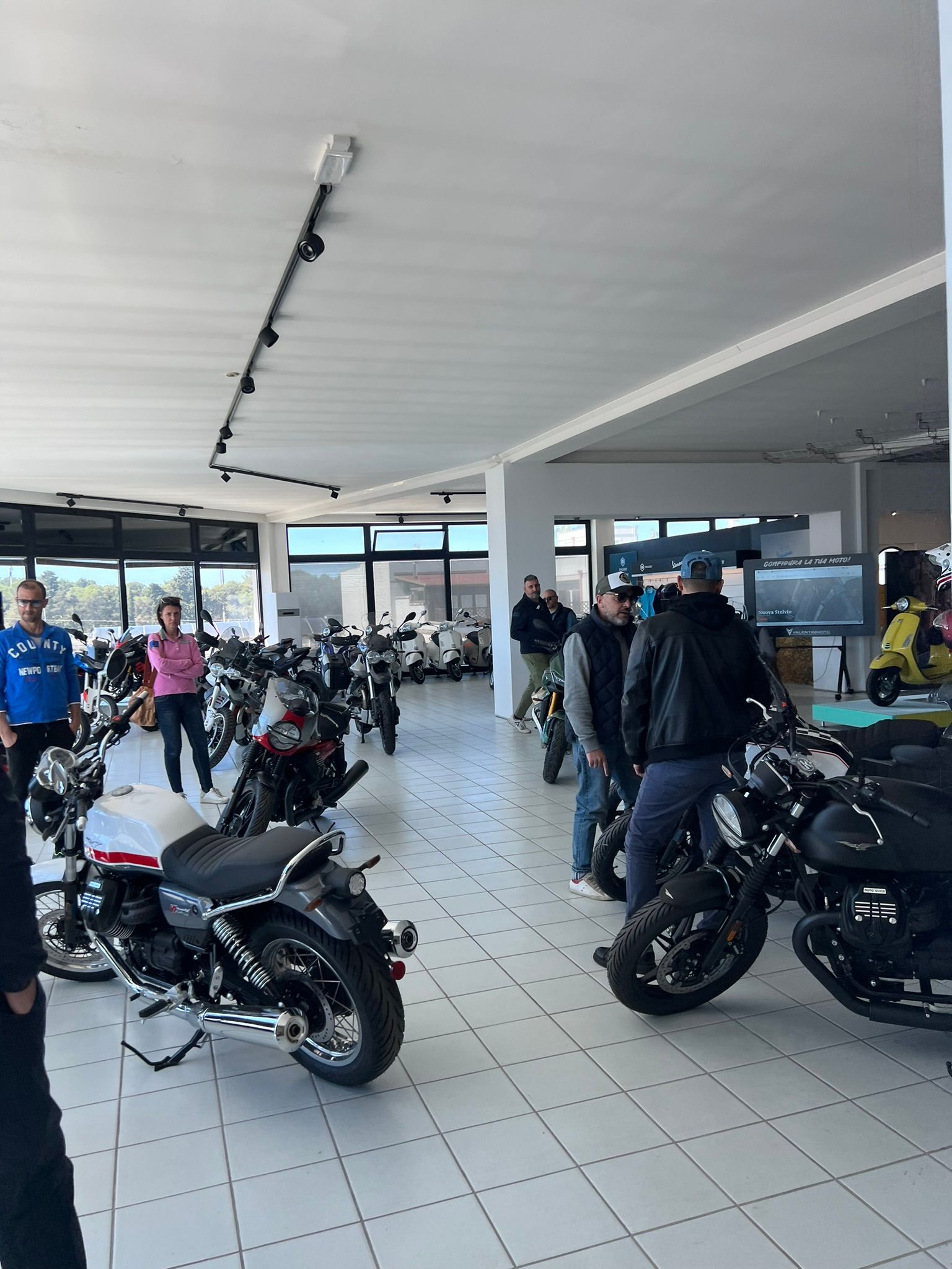 Un gruppo di persone è in piedi attorno alle moto in uno showroom.