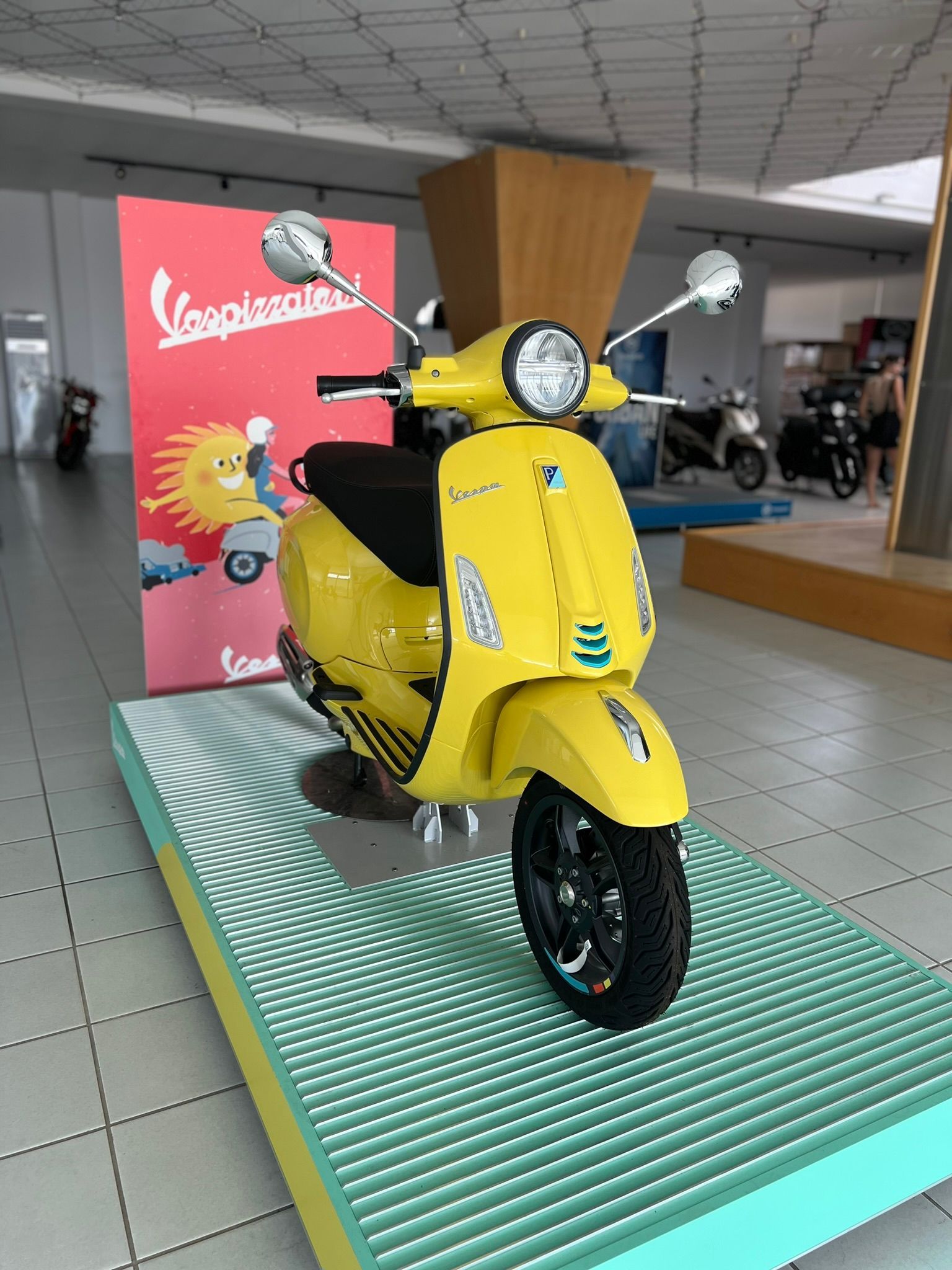 Uno scooter Vespa giallo è esposto in uno showroom.