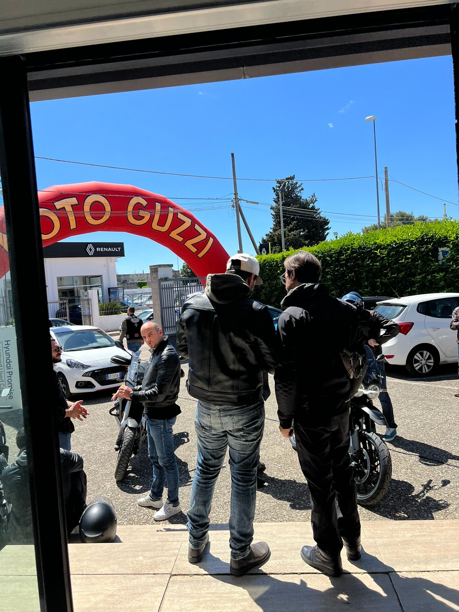 Un gruppo di persone in piedi davanti a un cartello rosso con la scritta moto Guzzi