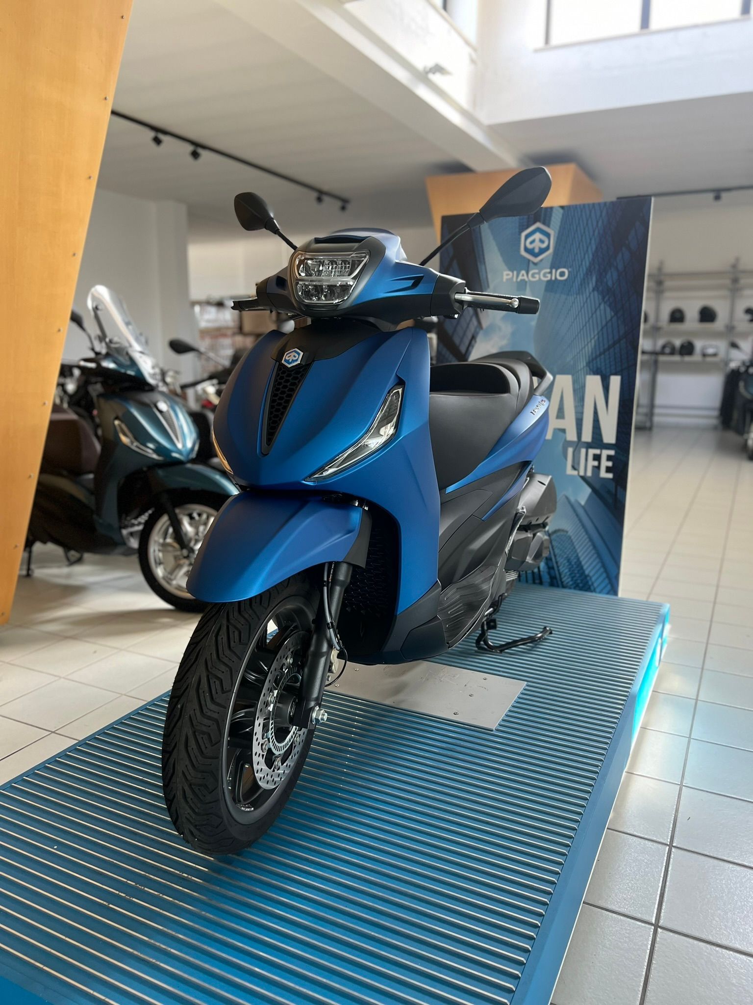 Uno scooter blu è esposto in uno showroom.