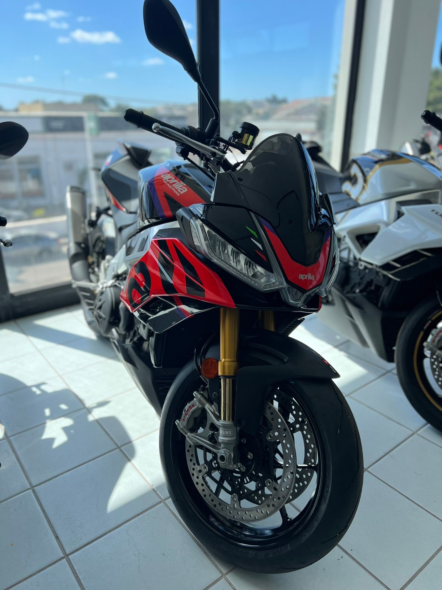 Una moto rossa e nera è parcheggiata in uno showroom.