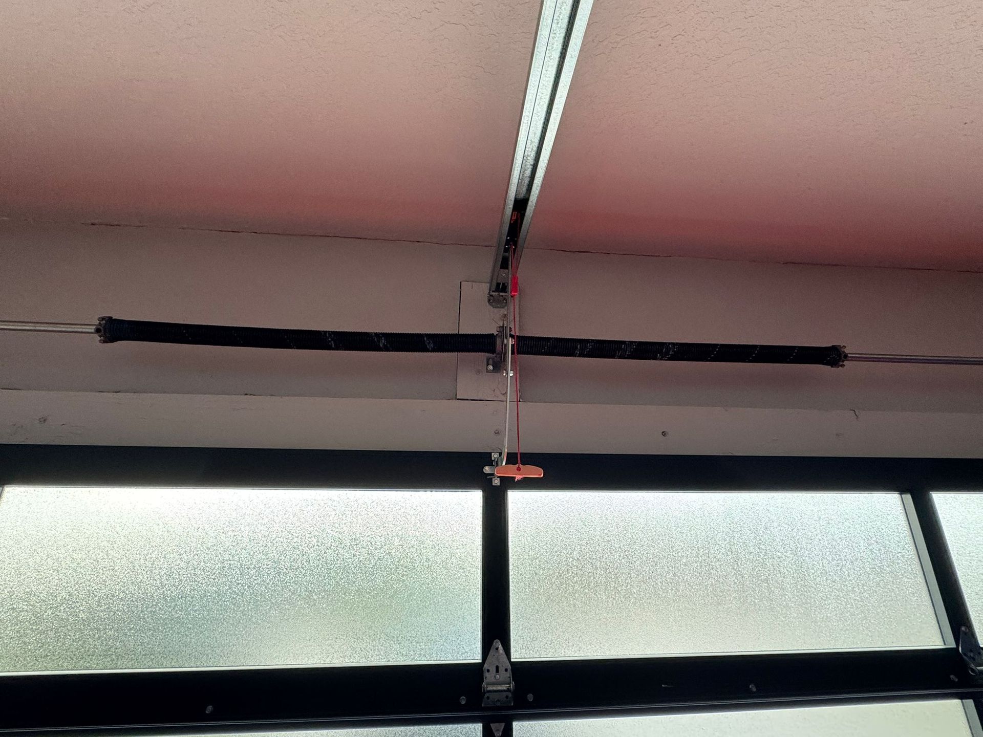 A close up of a garage door spring hanging from the ceiling