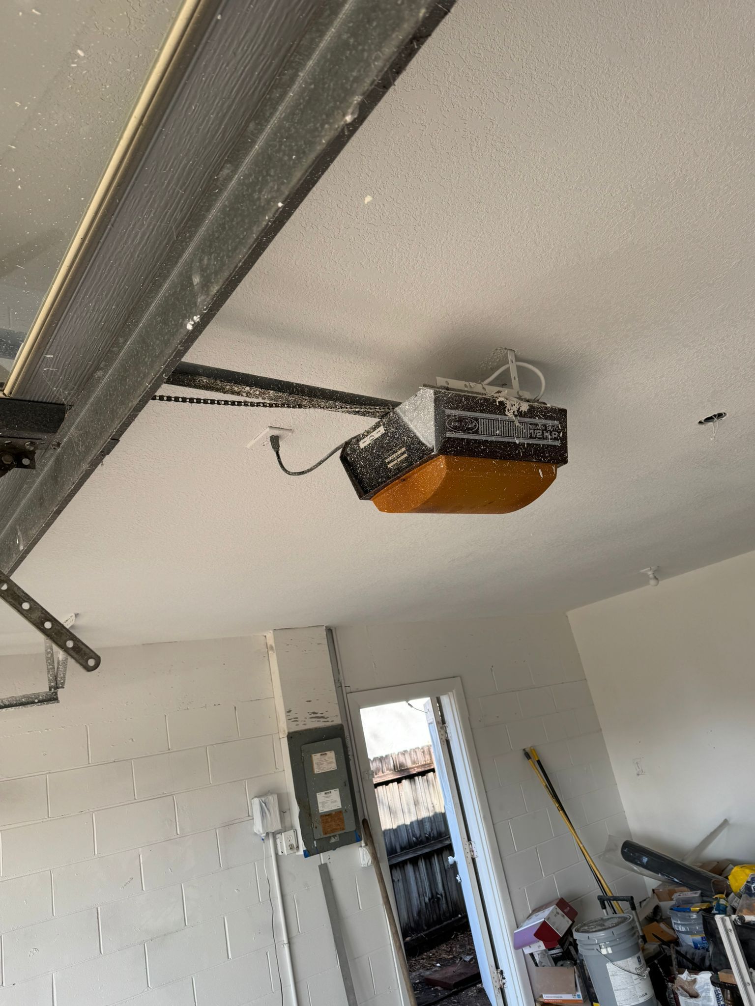 A garage door opener is hanging from the ceiling of a garage.
