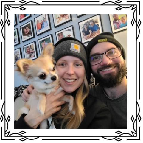 Woman, man, and small dog smile, posing for a photo.