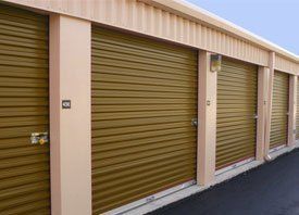A row of storage units with brown doors and a blue sky in the background.