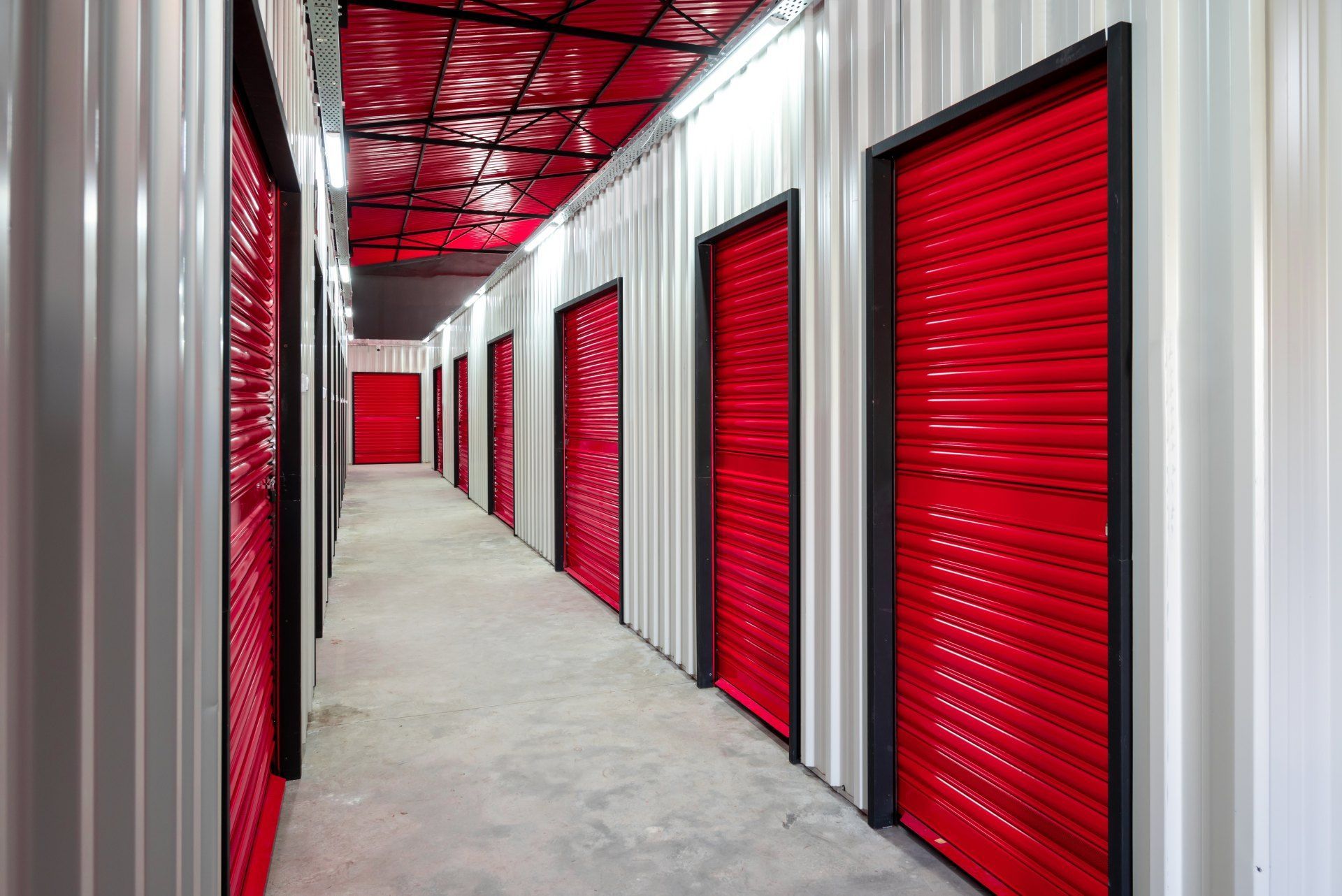 A long hallway with red doors in a storage facility.