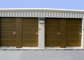 A row of storage units with brown doors and a blue sky in the background.