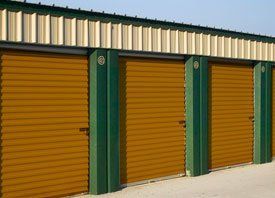 A row of storage units with yellow doors and green pillars.