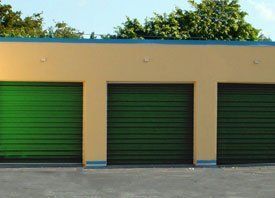 A yellow building with three green garage doors.