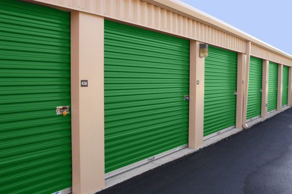 A row of green storage units with a blue sky in the background.