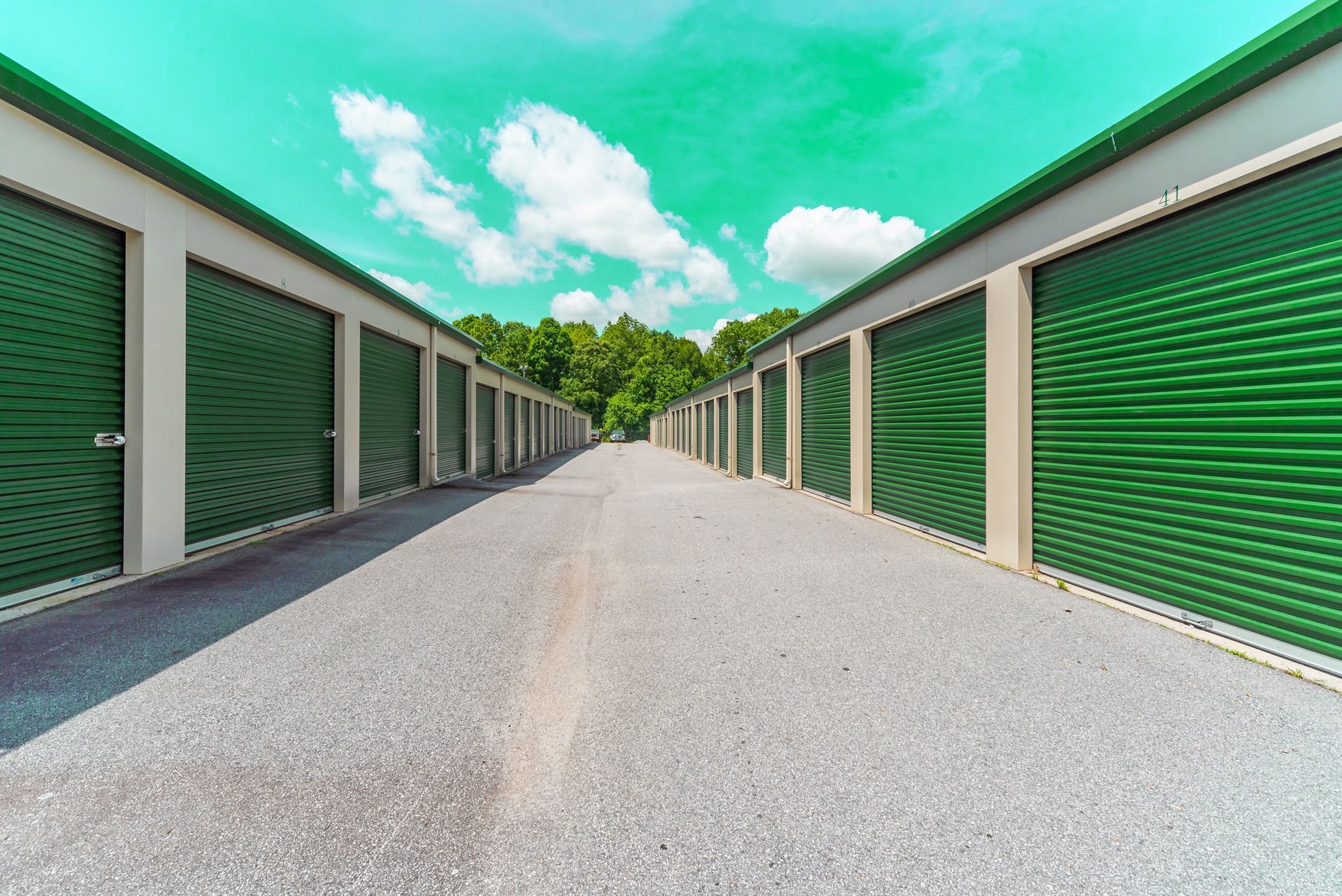 A row of green storage units along a road.
