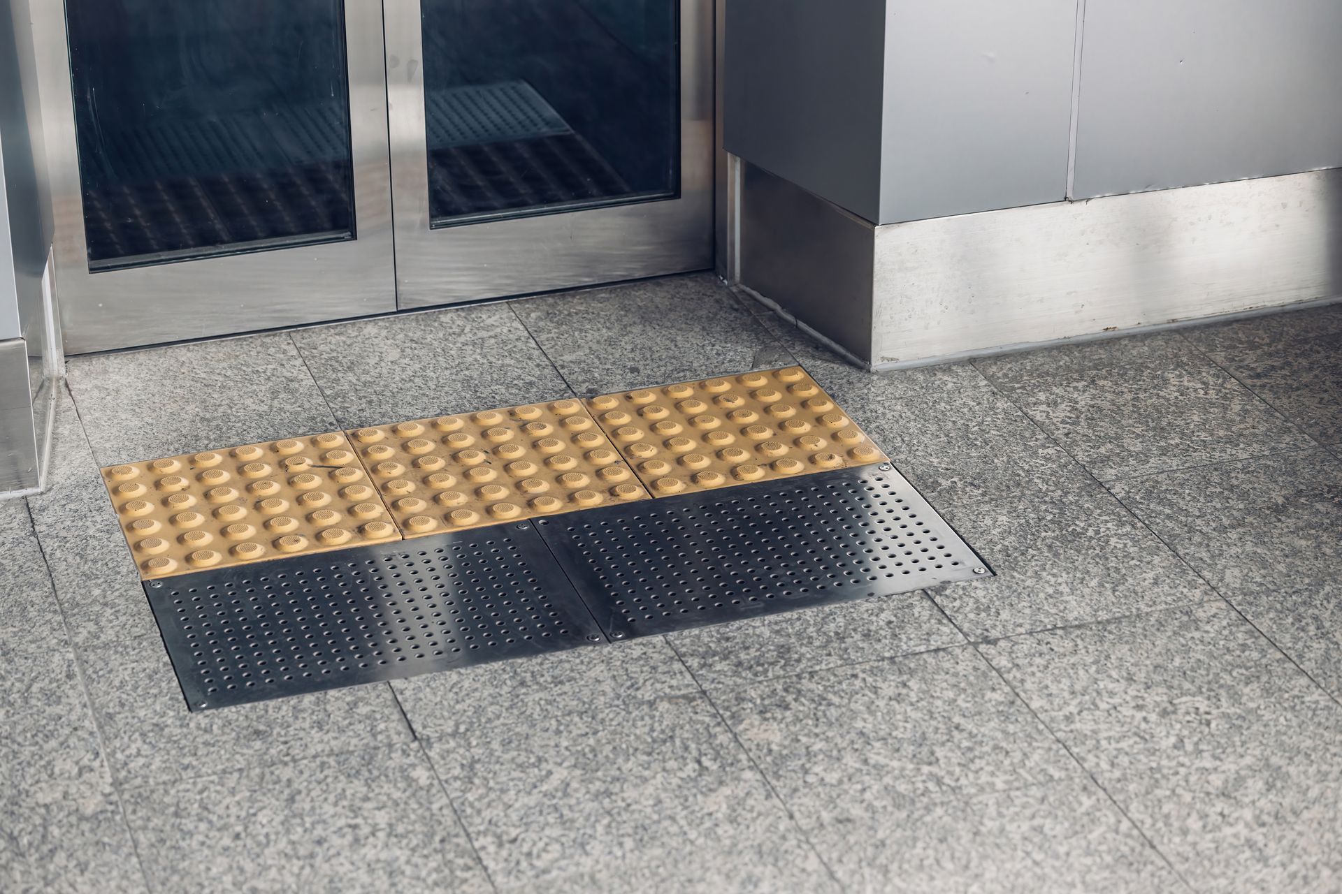 A gray tiled floor with a yellow bump on it next to a door.