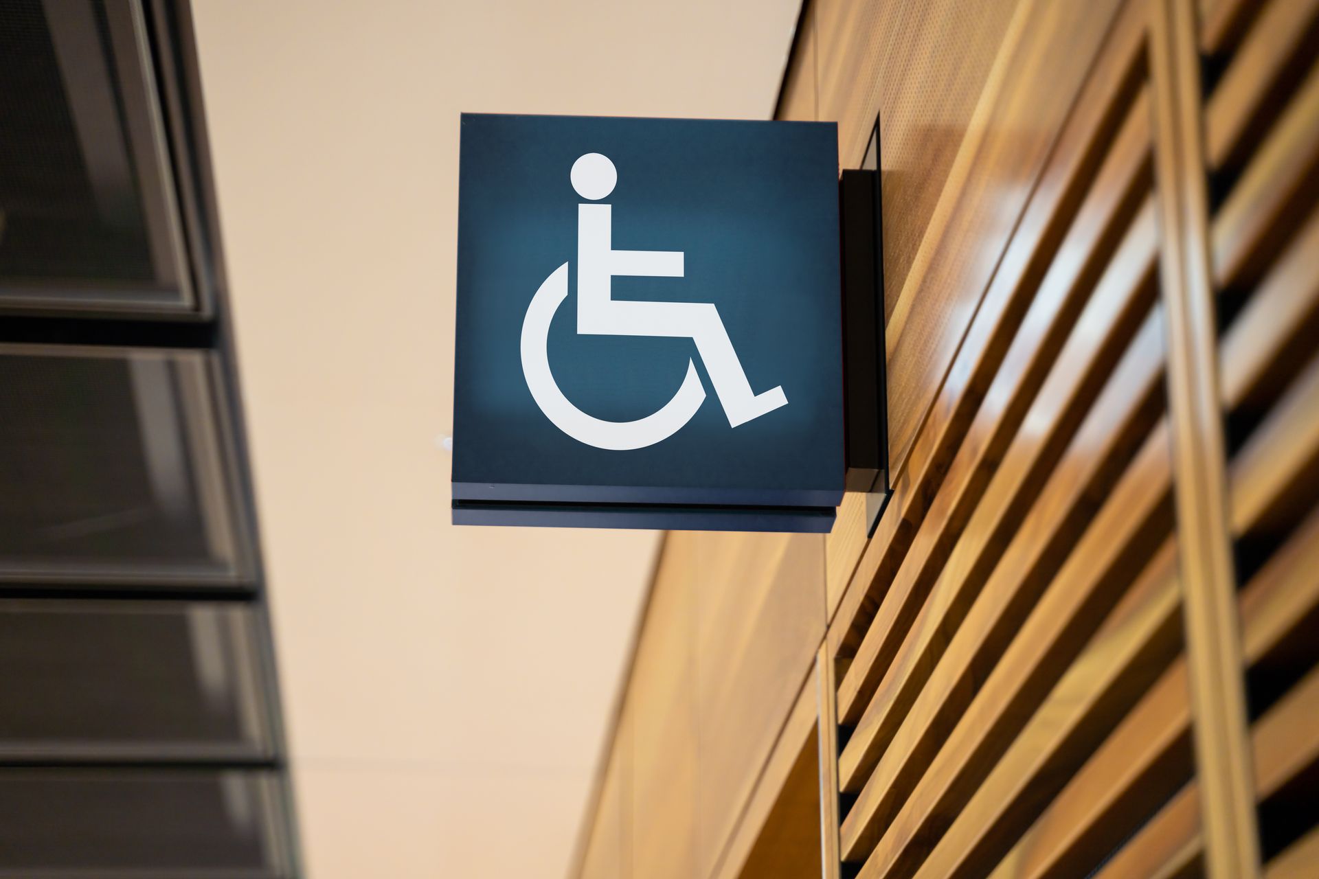 A handicap sign is hanging on a wooden wall