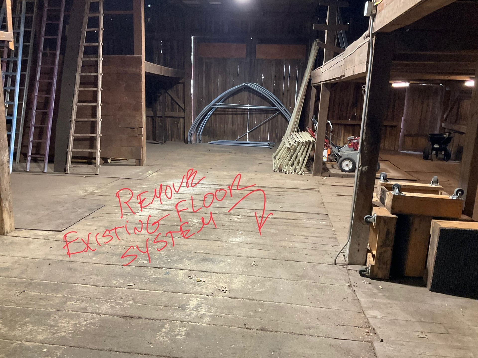 An empty barn with the words remove existing system written on the floor