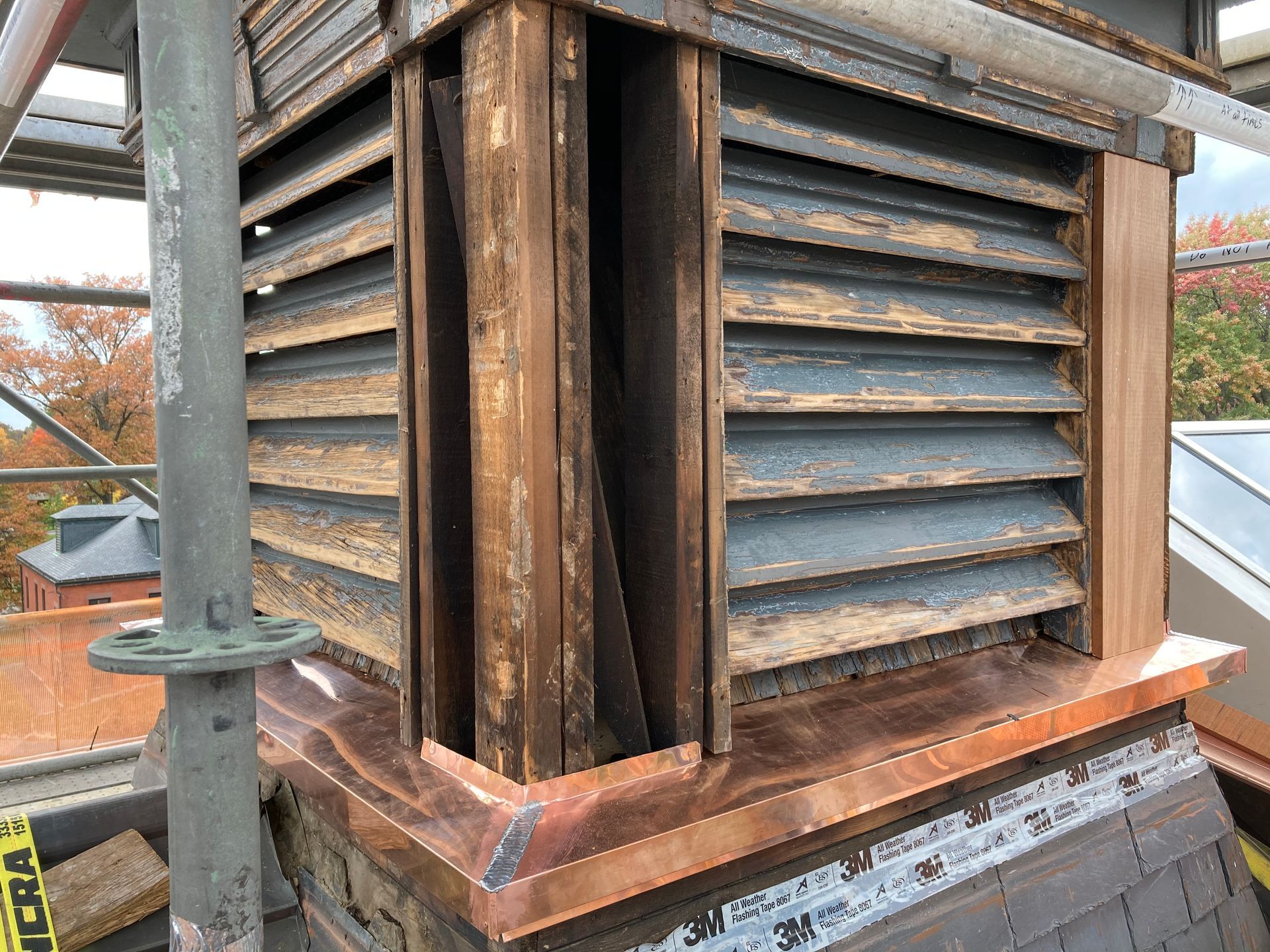 A chimney with wooden shutters on it is being repaired.