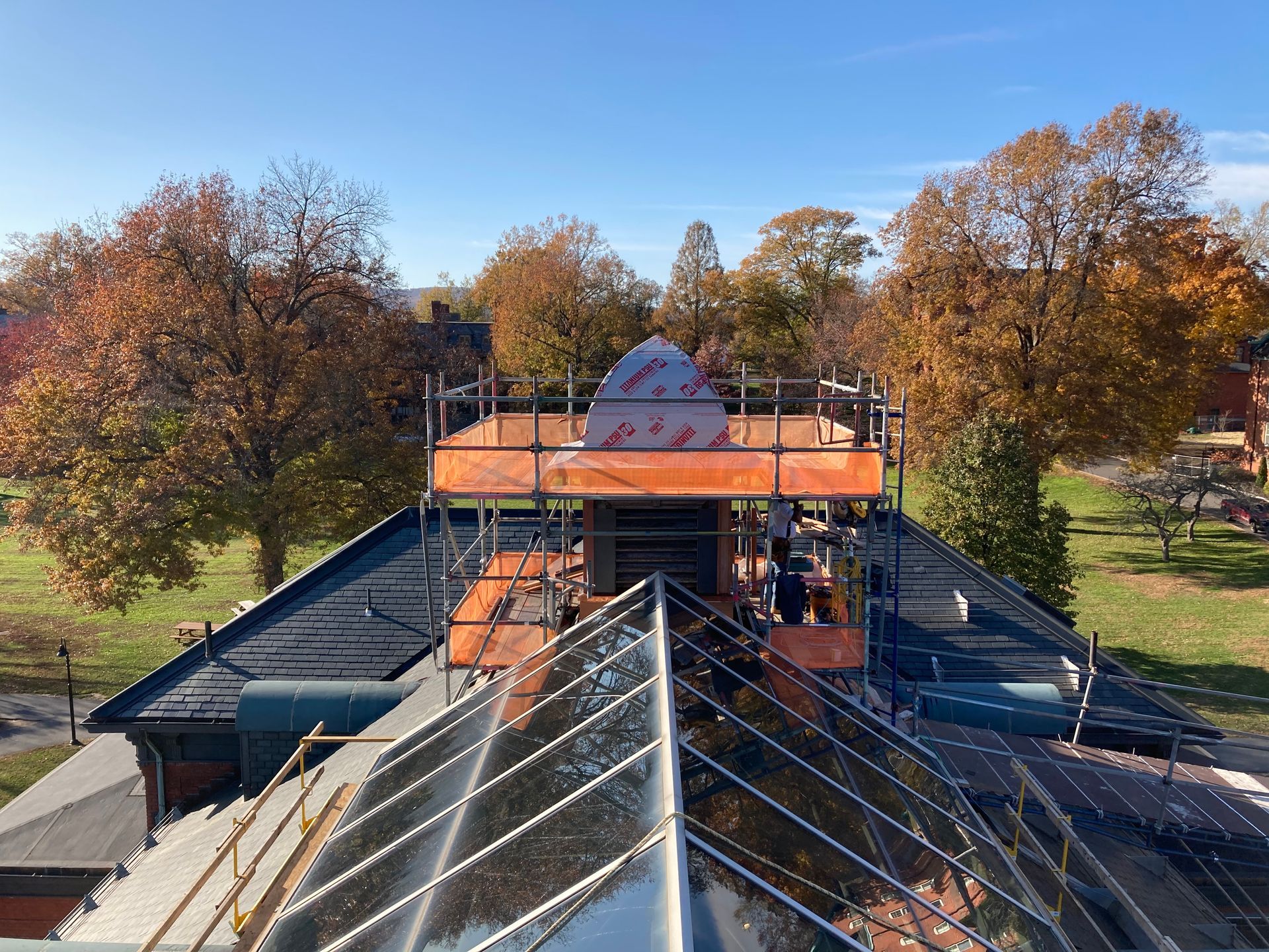 A roof with scaffolding on it and trees in the background.