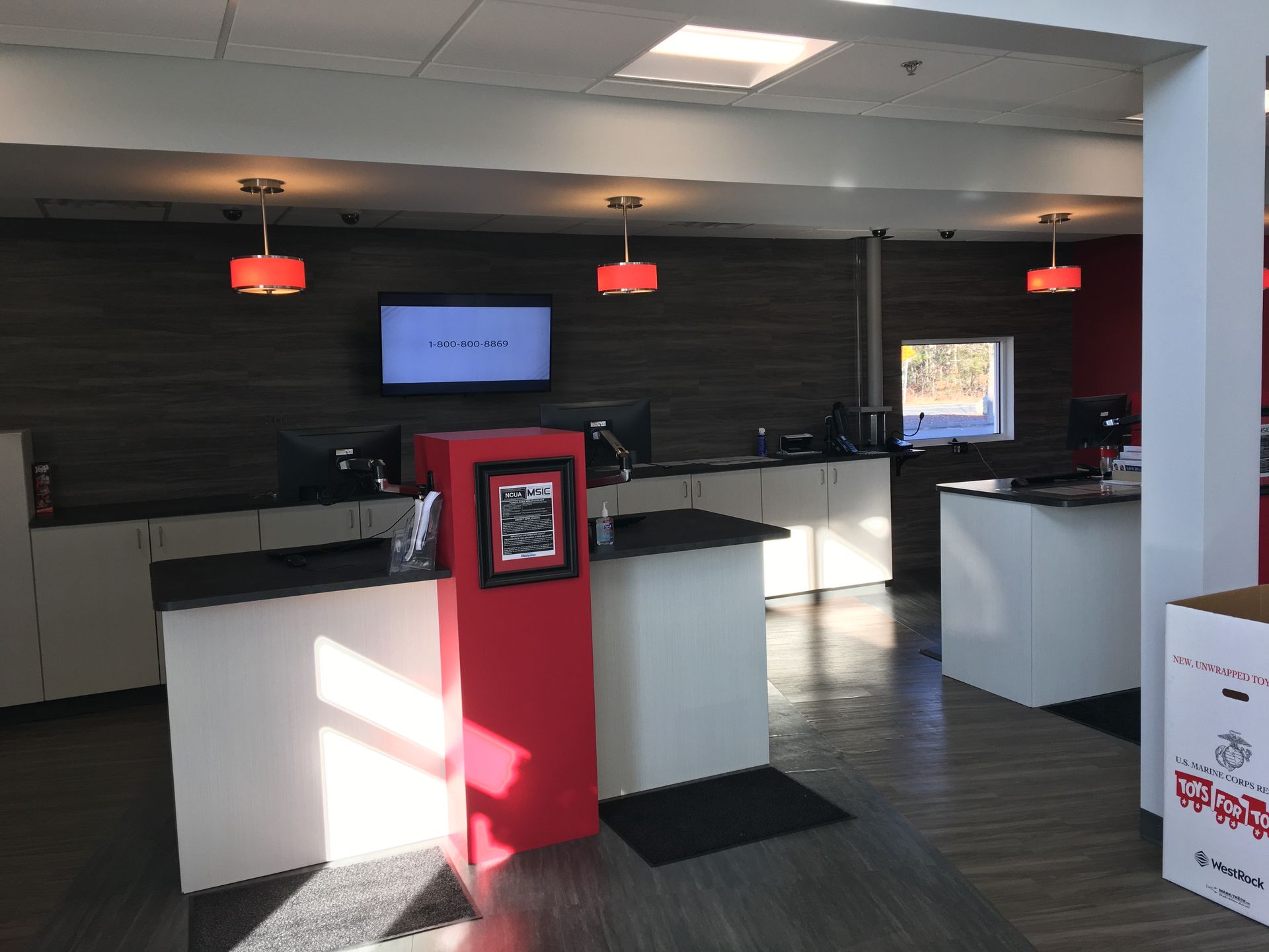 A large room with a red and white counter and a tv on the wall.
