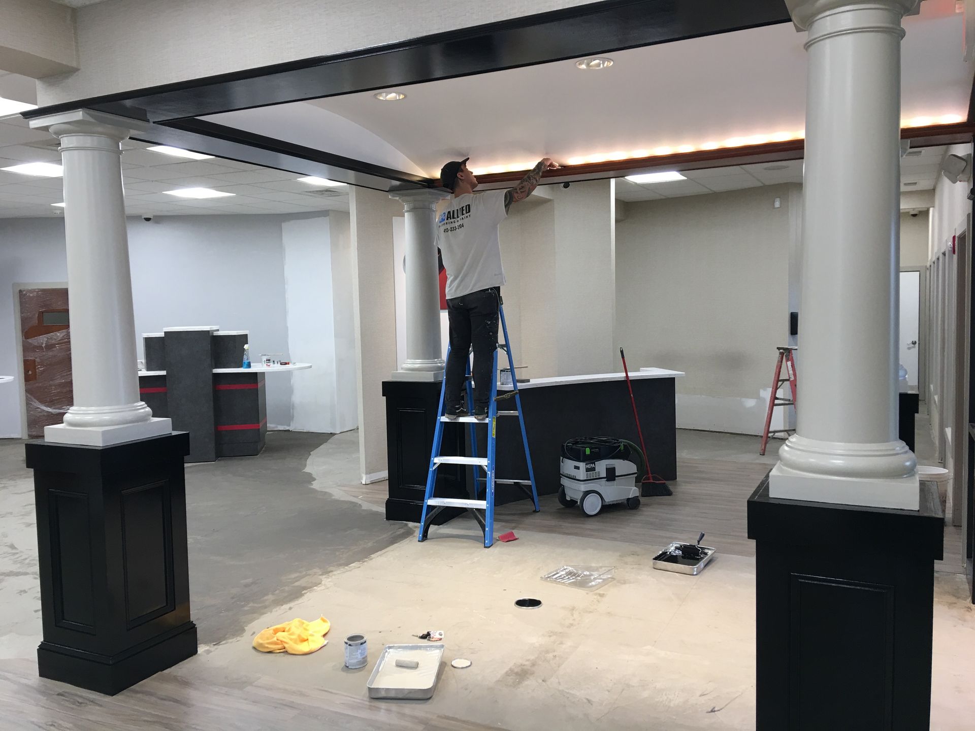 A man is standing on a ladder in an empty room.