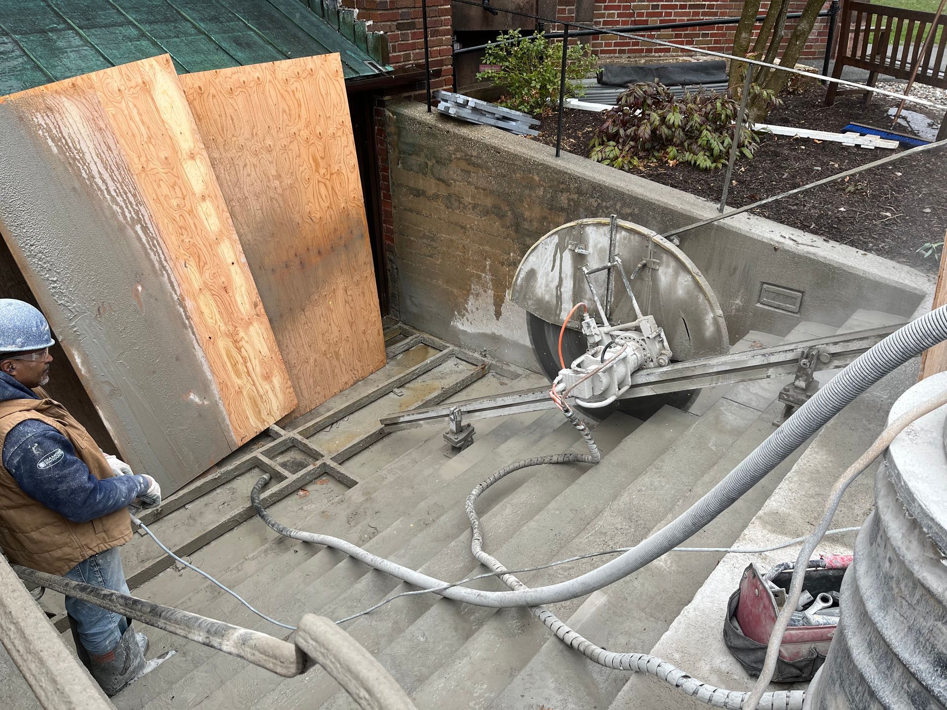 A man is cutting concrete with a circular saw on a set of stairs.