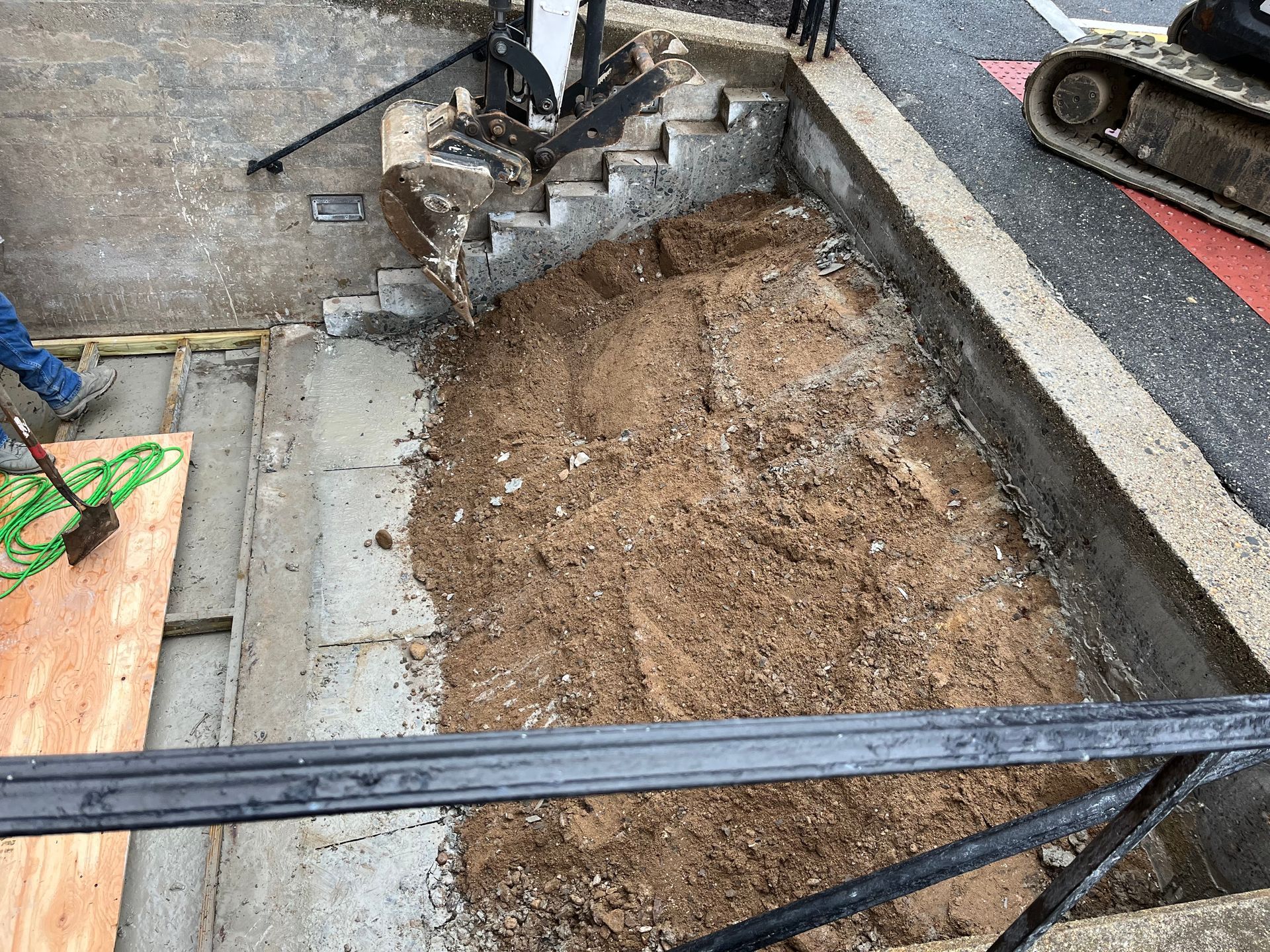 A pile of dirt is sitting on the ground next to a staircase.