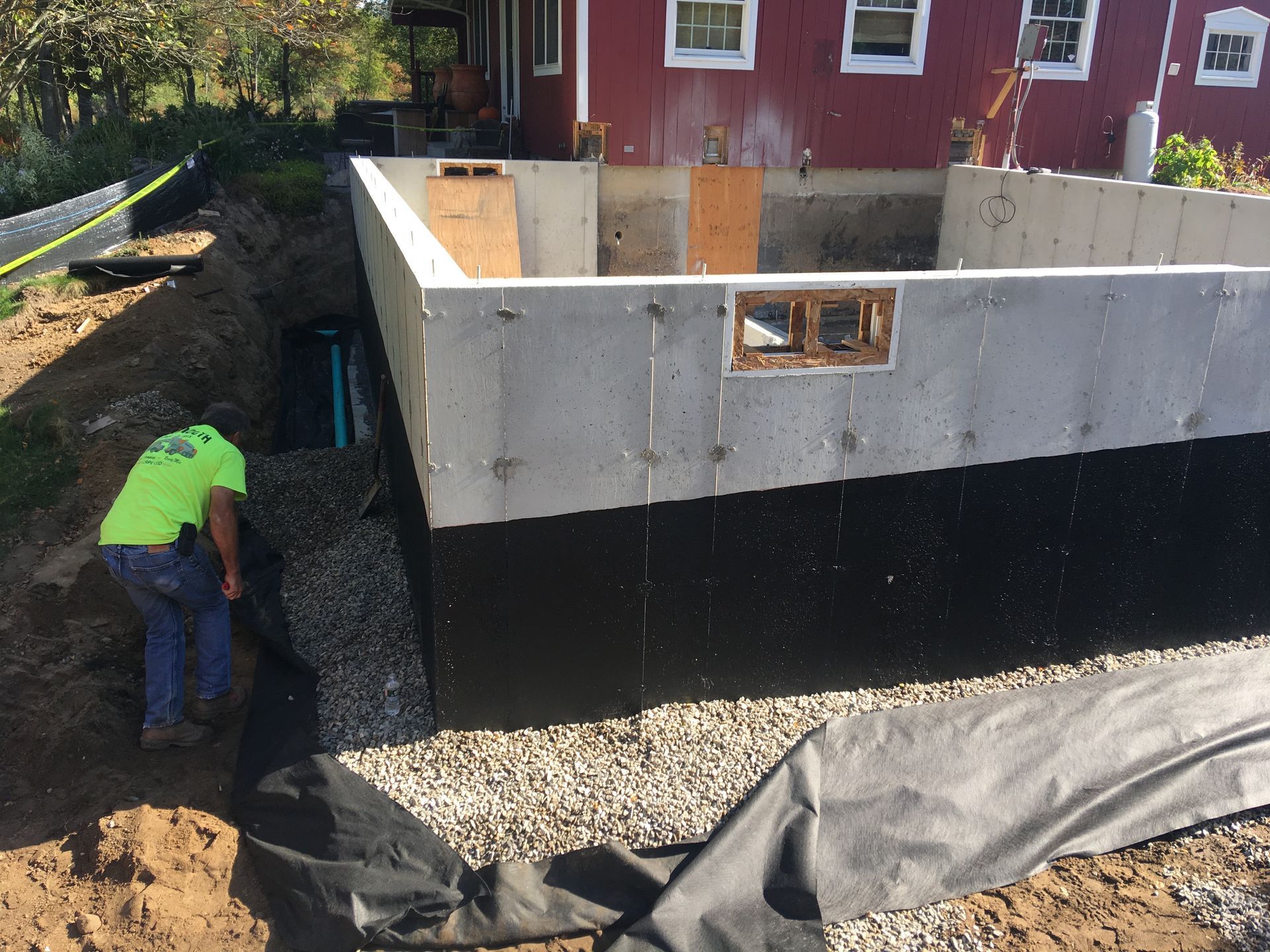 A man in a neon green shirt is standing in front of a concrete wall.