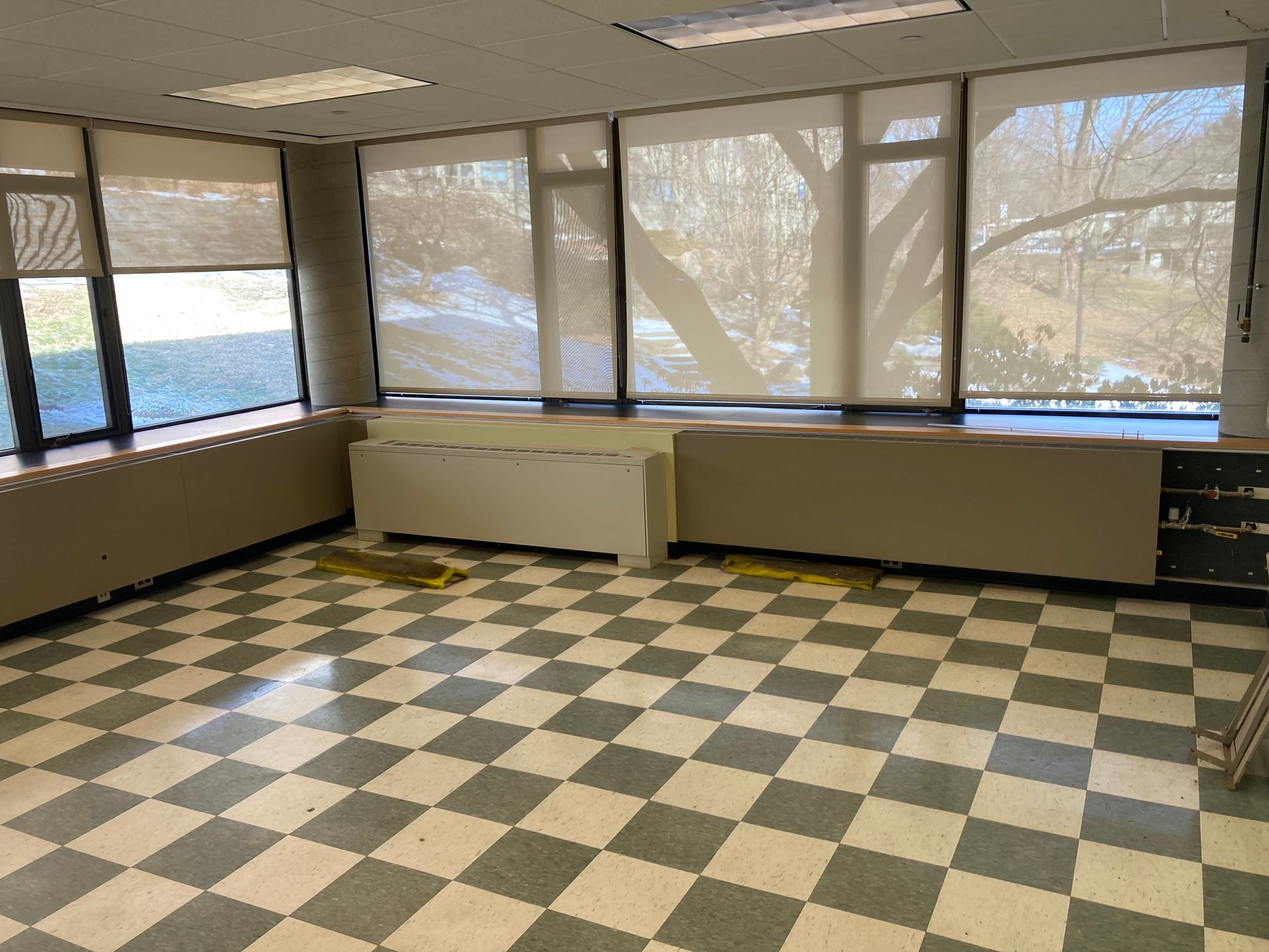 An empty room with a checkered floor and lots of windows.