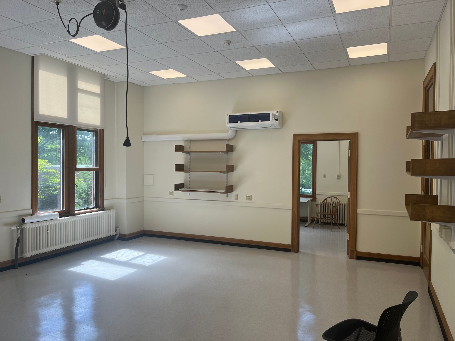 A large empty room with a lot of windows and a ceiling fan.