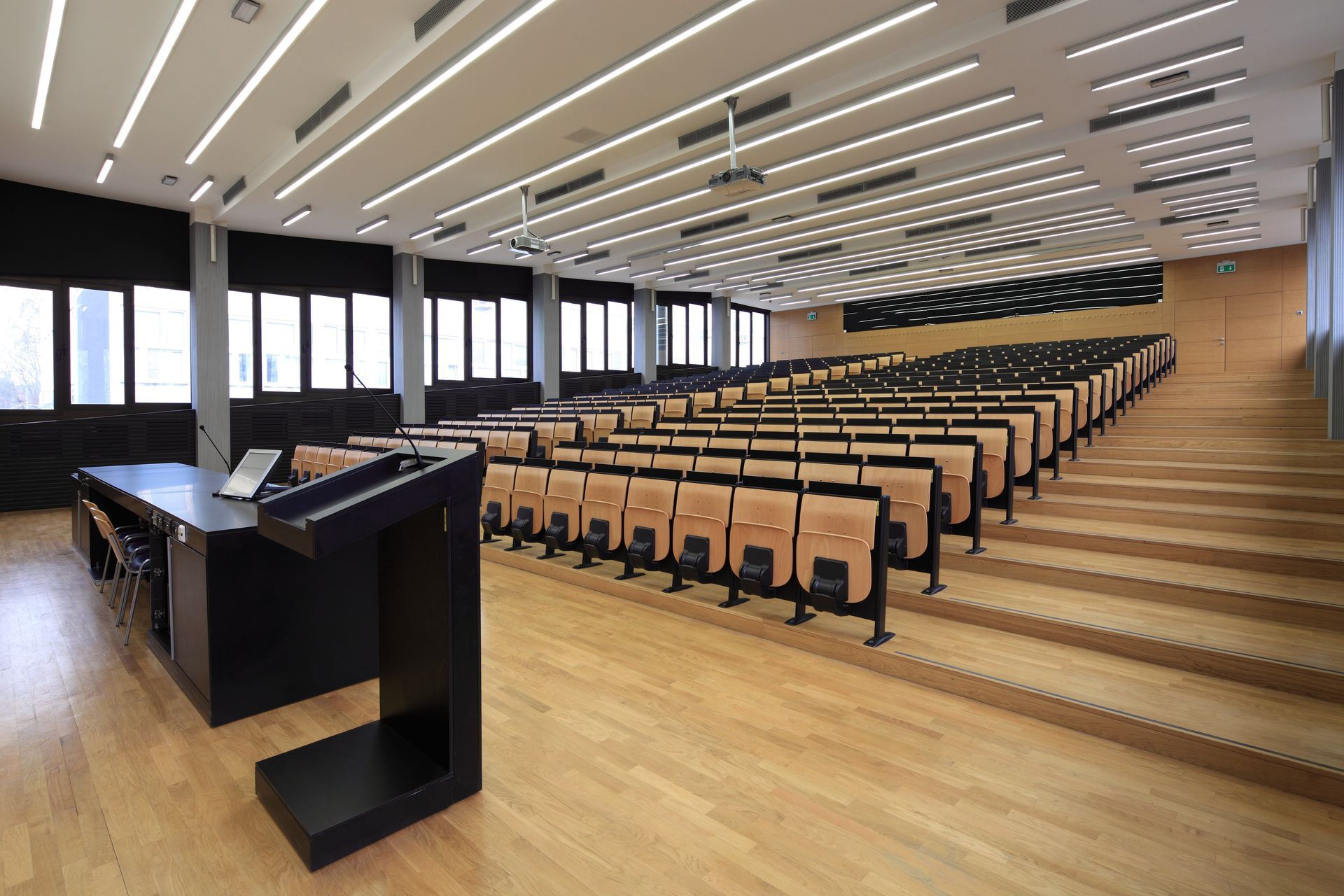 A large auditorium with rows of wooden seats and a podium.