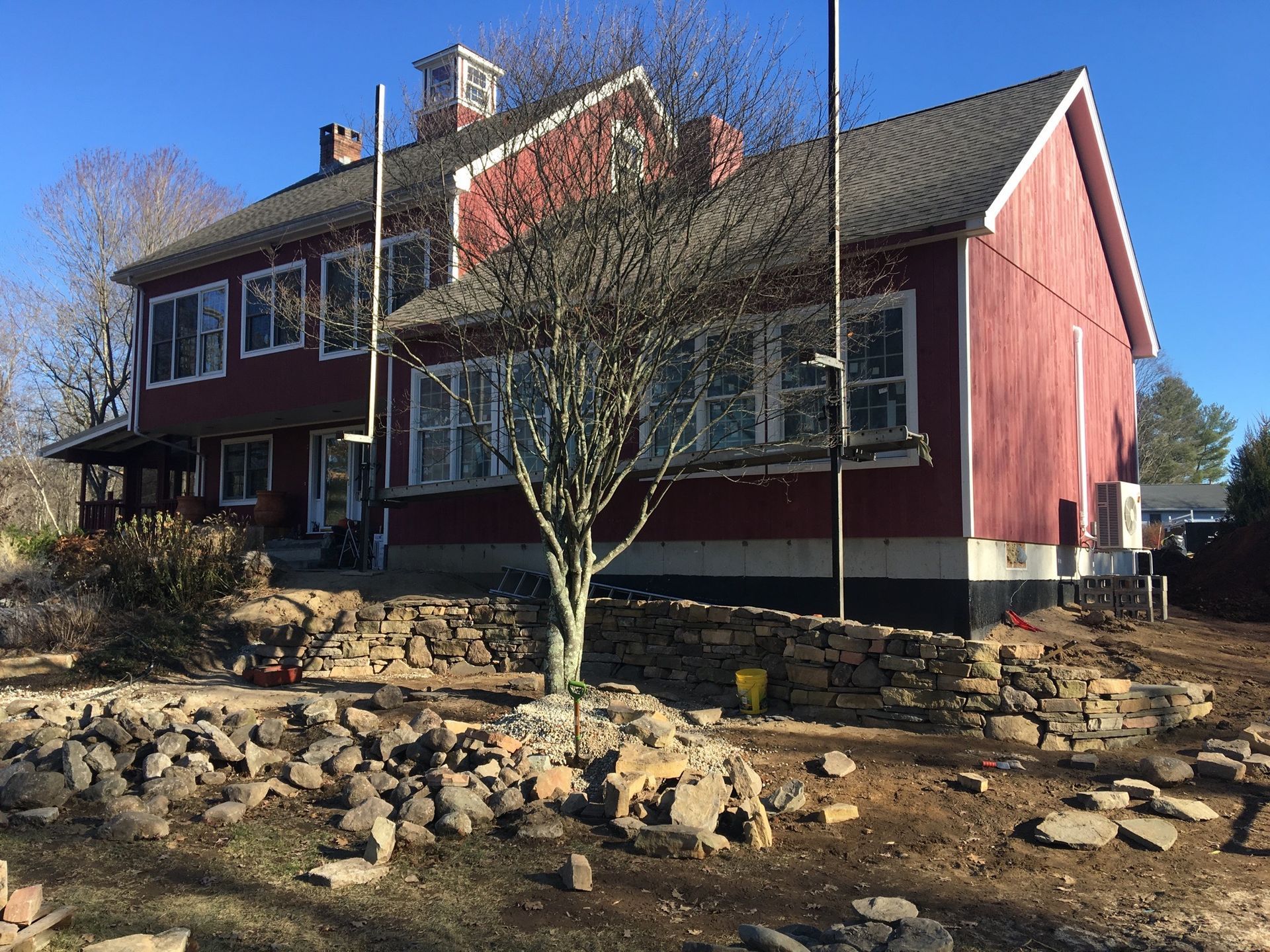 A large red house with a stone wall in front of it.