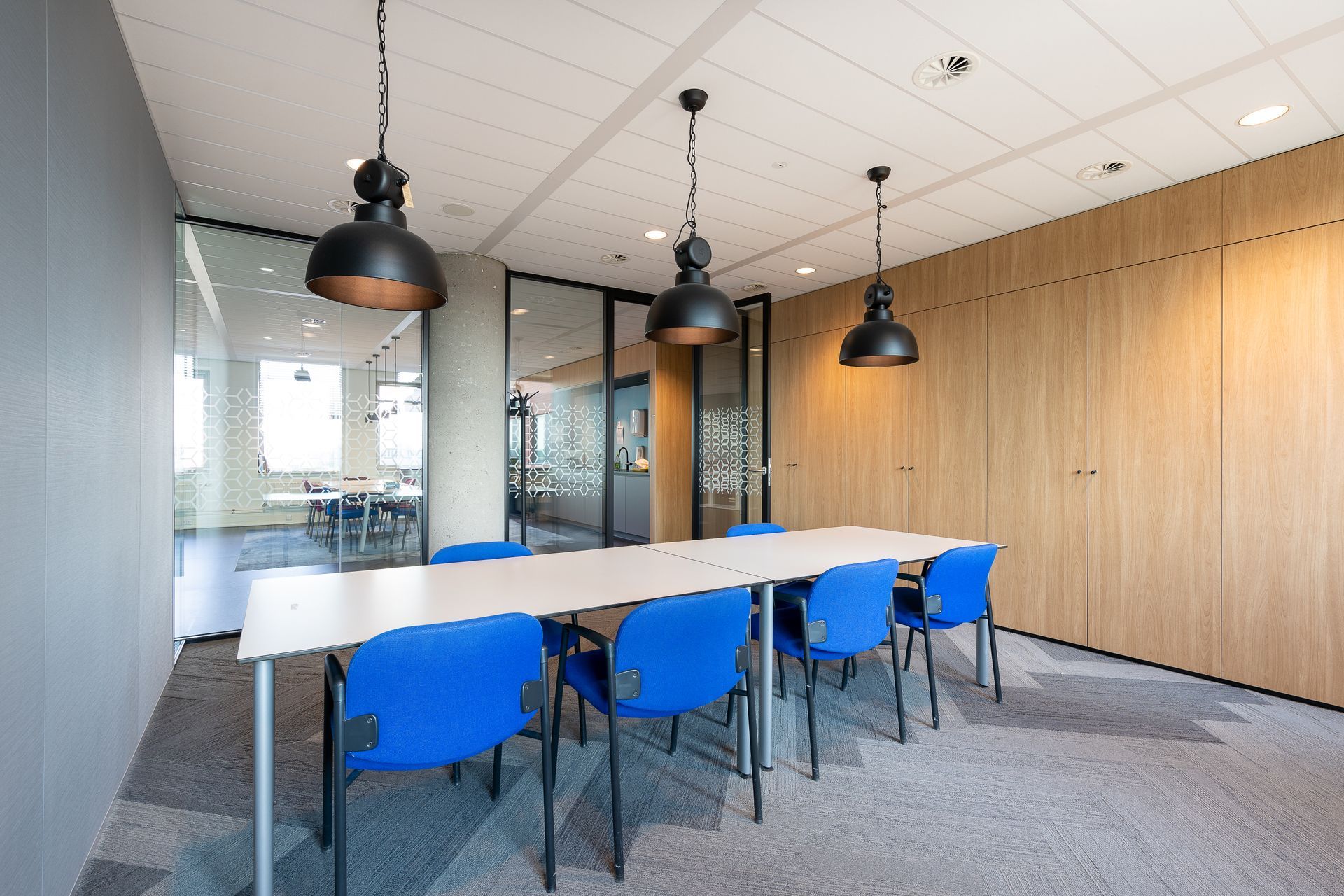 A conference room with a long table and blue chairs.