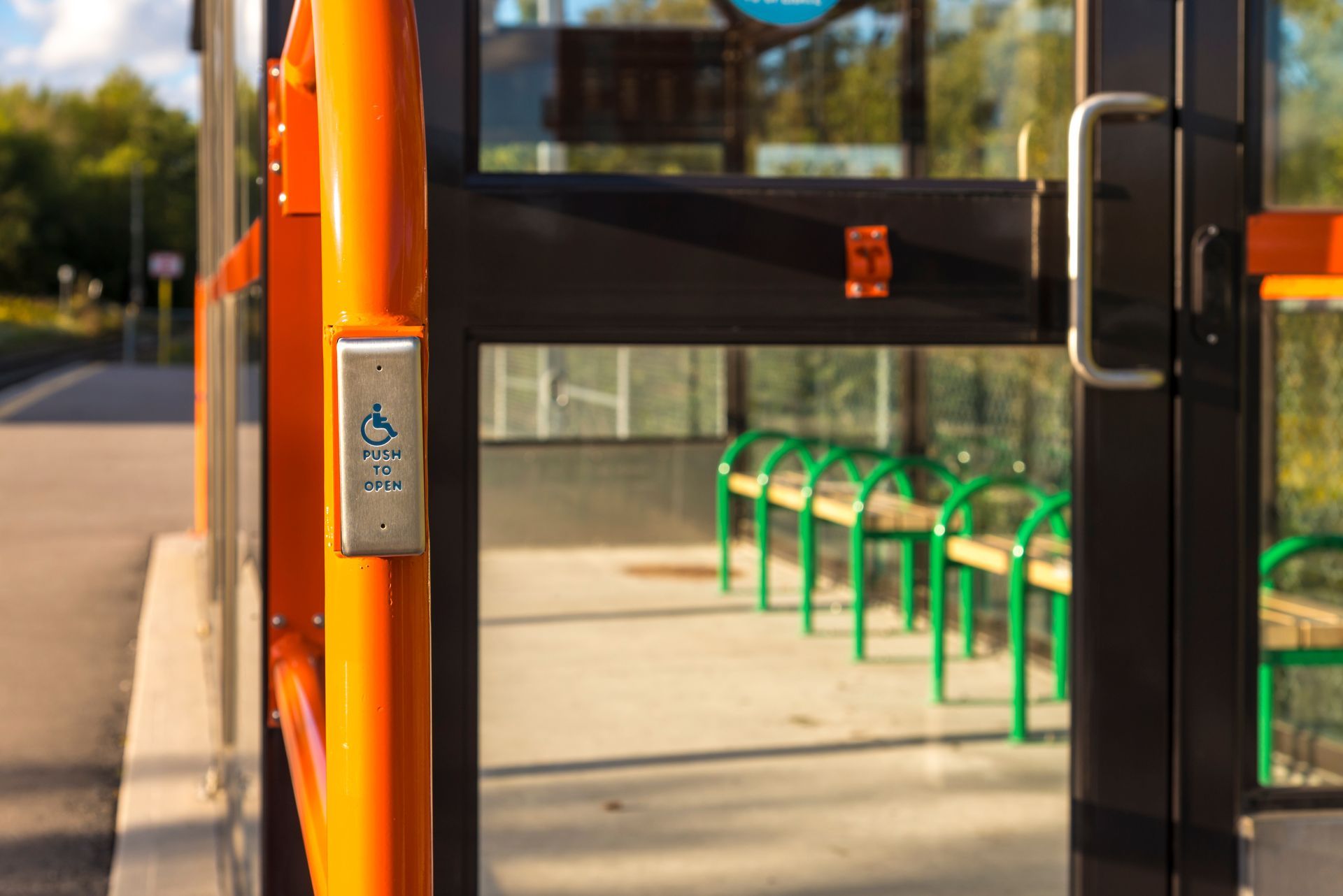 A bus stop with a row of green chairs and a door open.