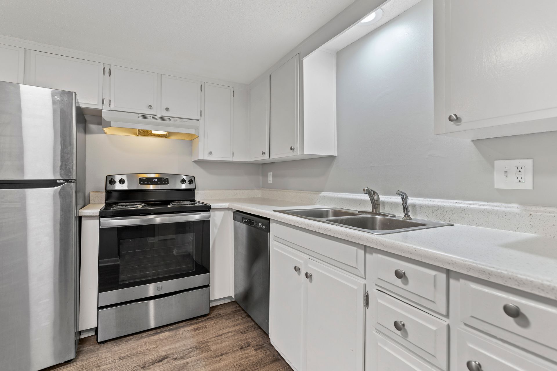 White kitchen with stainless steel appliances and light countertops.