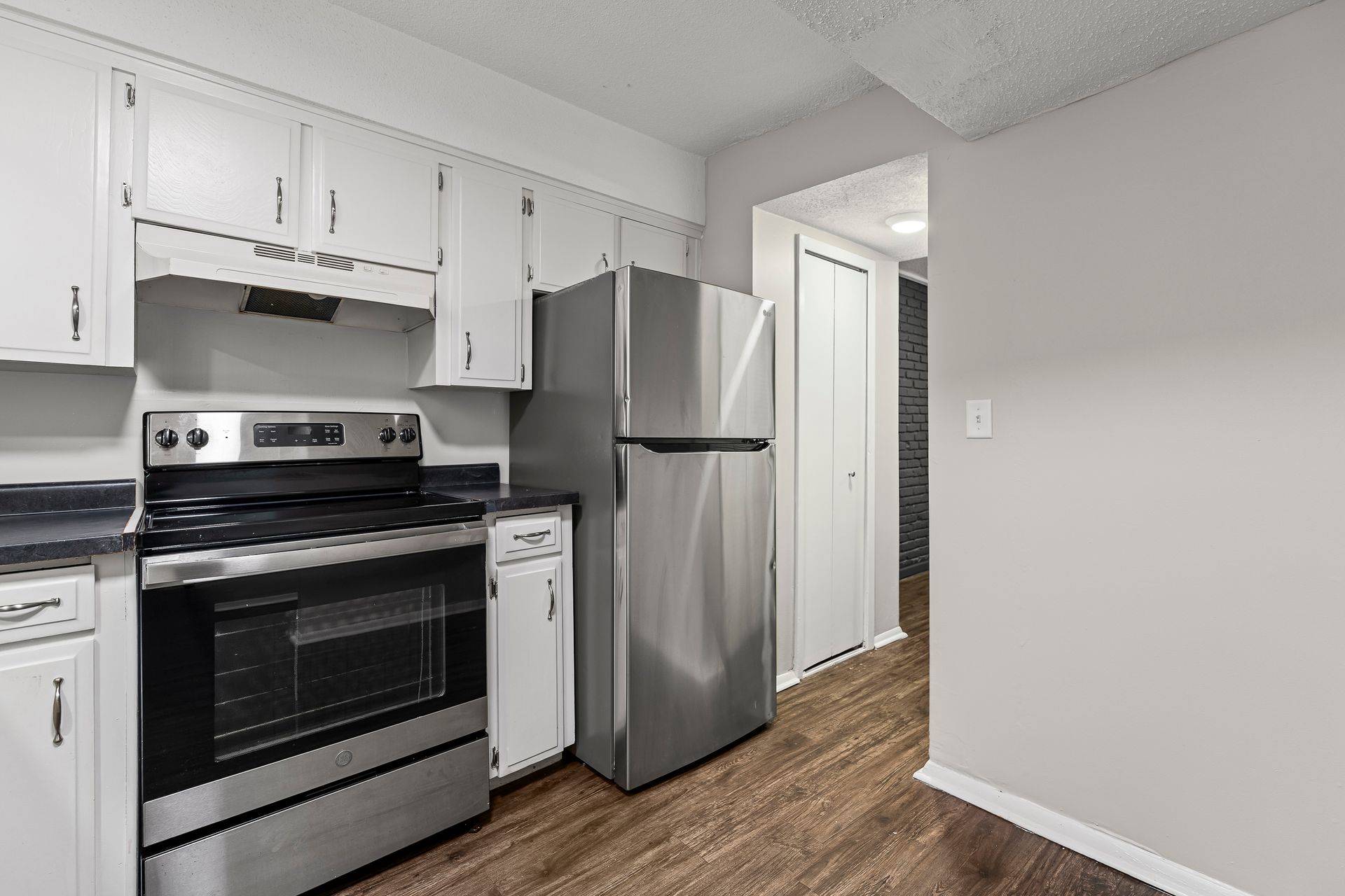 Kitchen with white cabinets, stainless steel appliances, and dark wood flooring.
